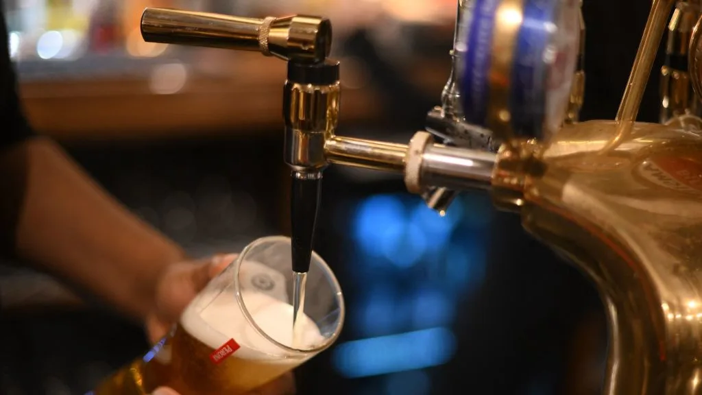 An employee pours a pint of Peroni beer on at the bar in the Mad Hatter pub and hotel, operated by