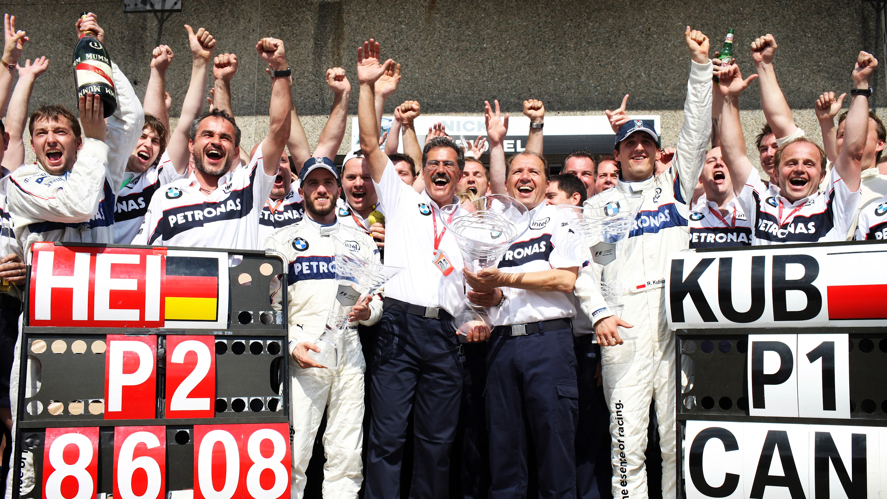 BMW Sauber team members Nick Heidfeld (centre left blue cap), Mario Theissen (centre left holding