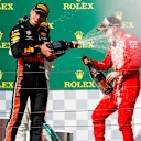 HUNGARORING, HUNGARY - AUGUST 04: Max Verstappen, Red Bull Racing, 2nd position, blasts Sebastian Vettel, Ferrari, 3rd position, with Champagne during the Hungarian GP at Hungaroring on August 04, 2019 in Hungaroring, Hungary. (Photo by Zak Mauger / LAT Images)