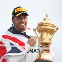 SILVERSTONE, UNITED KINGDOM - JULY 14: Race winner Lewis Hamilton, Mercedes AMG F1 celebrates on the podium with the trophy and with a flag during the British GP at Silverstone on July 14, 2019 in Silverstone, United Kingdom. (Photo by Joe Portlock / LAT Images)