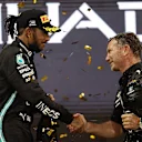 ABU DHABI, UNITED ARAB EMIRATES - DECEMBER 12: Red Bull Racing Team Principal Christian Horner shakes hands with second placed Lewis Hamilton of Great Britain and Mercedes GP on the podium during the F1 Grand Prix of Abu Dhabi at Yas Marina Circuit on December 12, 2021 in Abu Dhabi, United Arab Emirates. (Photo by Lars Baron/Getty Images)