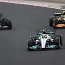 BUDAPEST, HUNGARY - JULY 31: Lewis Hamilton of Great Britain driving the (44) Mercedes AMG Petronas F1 Team W13 leads Max Verstappen of the Netherlands driving the (1) Oracle Red Bull Racing RB18 and Lando Norris of Great Britain driving the (4) McLaren MCL36 Mercedes during the F1 Grand Prix of Hungary at Hungaroring on July 31, 2022 in Budapest, Hungary. (Photo by Dan Istitene - Formula 1/Formula 1 via Getty Images)