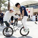 BAHRAIN, BAHRAIN - MARCH 04: Yuki Tsunoda of Japan and Scuderia AlphaTauri and Viki Gomez practice bicycle tricks in the Paddock prior to final practice ahead of the F1 Grand Prix of Bahrain at Bahrain International Circuit on March 04, 2023 in Bahrain, Bahrain. (Photo by Peter Fox/Getty Images)