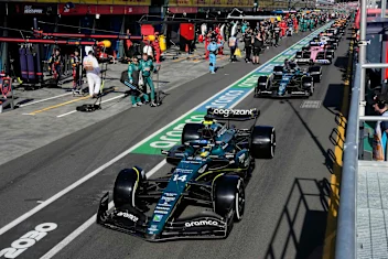 Aston Martin's Spanish driver Fernando Alonso and other drivers line up in the pit lane during a