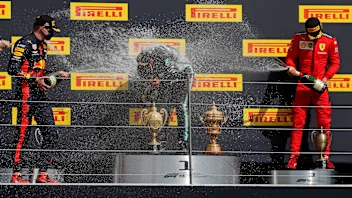 Mercedes' British driver Lewis Hamilton (C) is sprayed with champagne by second-placed Red Bull's
