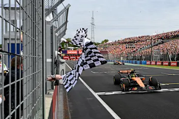 BUDAPEST, HUNGARY - AUGUST 03: Axl Rose waves the chequered flag as Race winner Lando Norris of