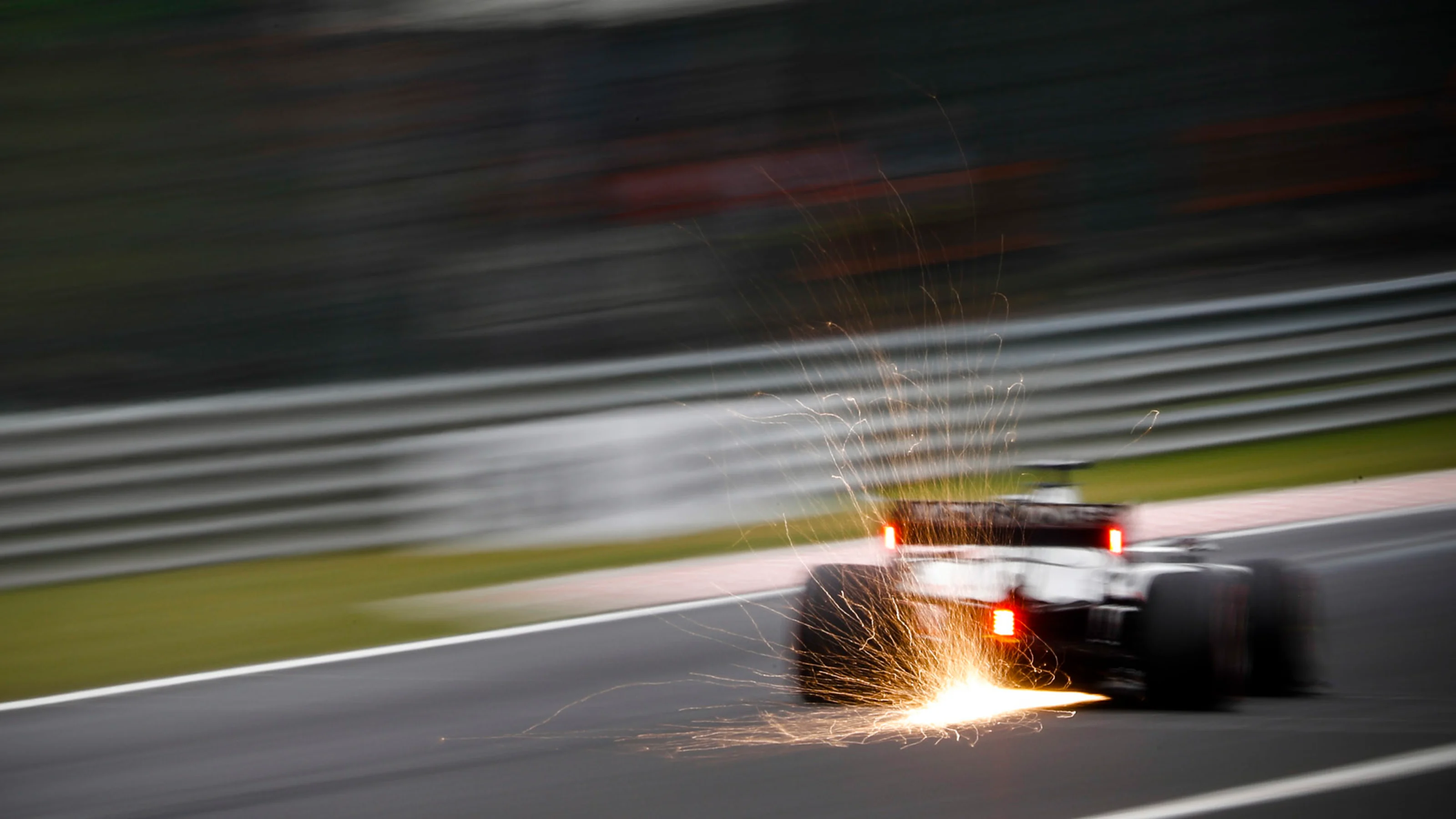 Sparks fly from the rear of Romain Grosjean, Haas