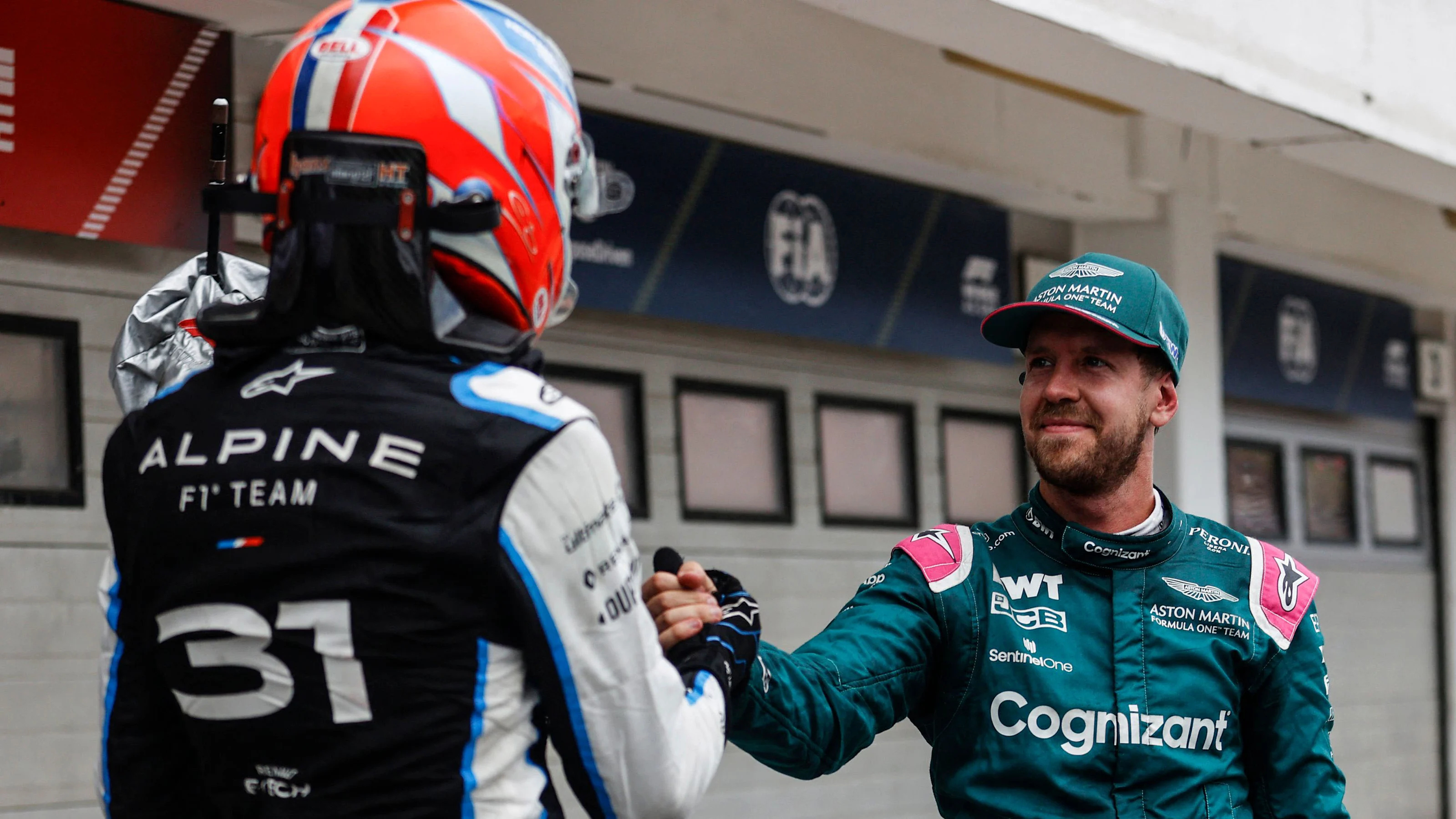 Alpine's French driver Esteban Ocon shakes hands with Aston Martin's German driver Sebastian Vettel