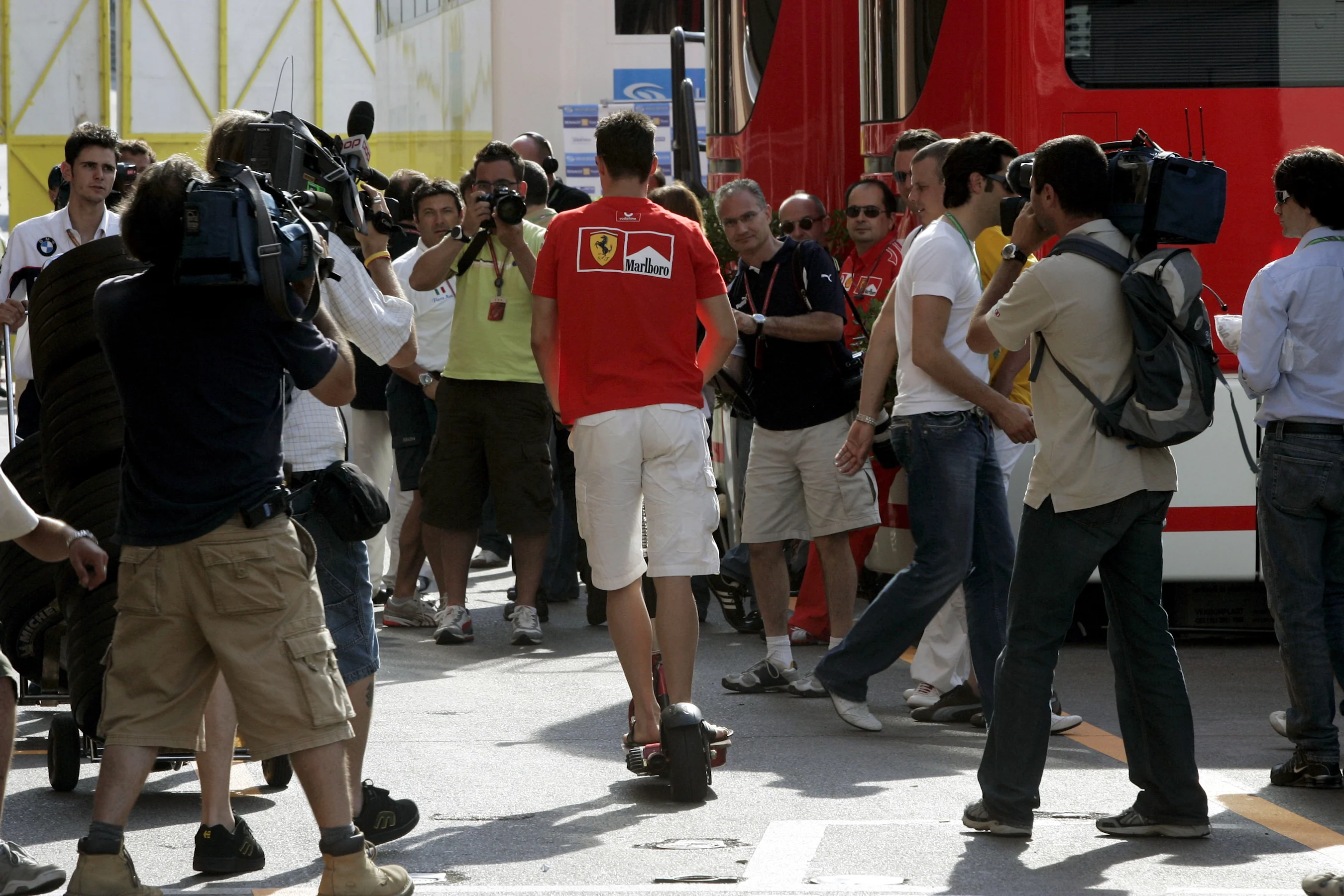 Michael Schumacher (GER) Ferrari negotiates the media in the paddock on his scooter. Formula One