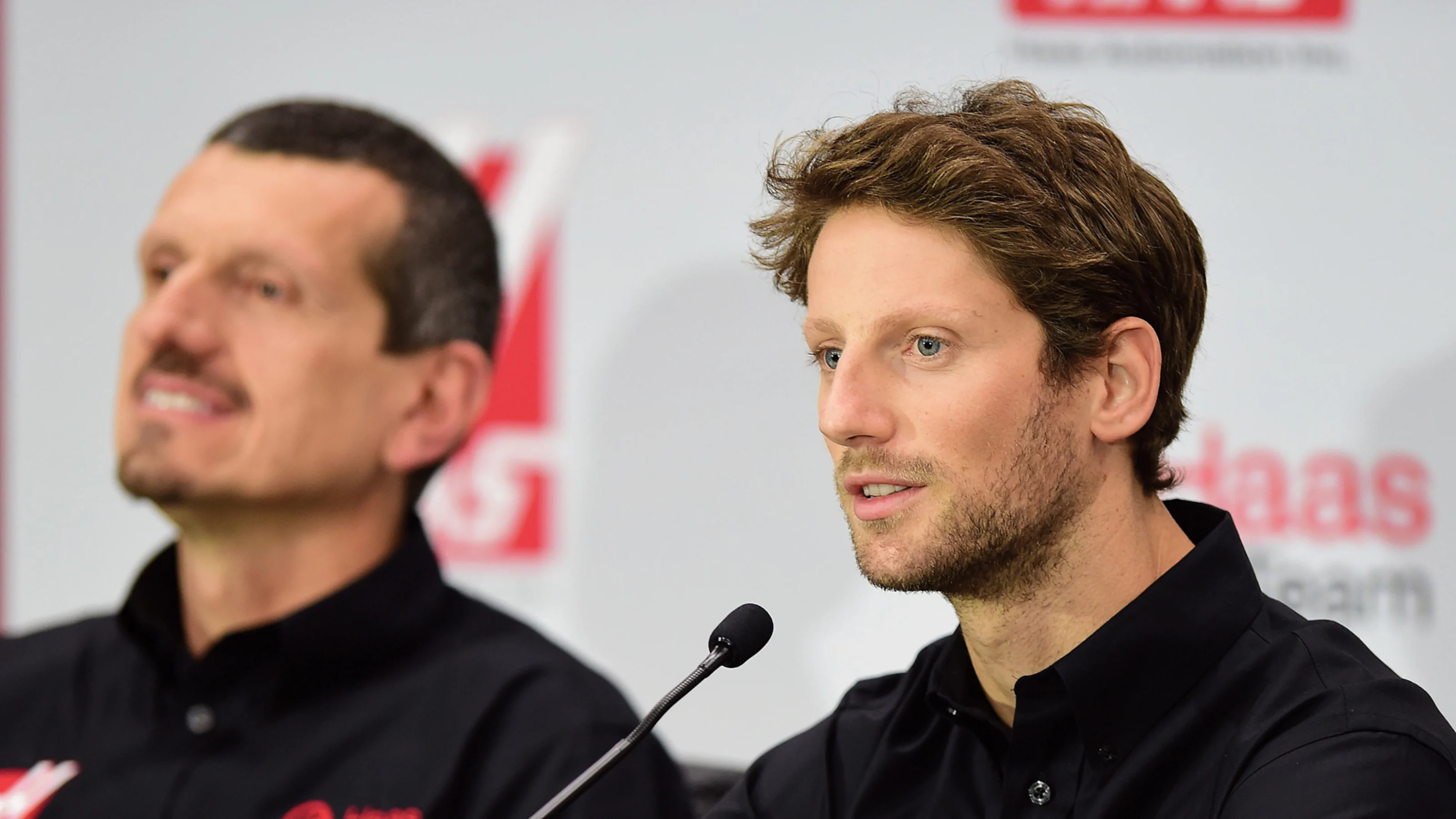 Romain Grosjean of France speaks as Gunther Steiner, team principal of Haas F1 Team, looks on