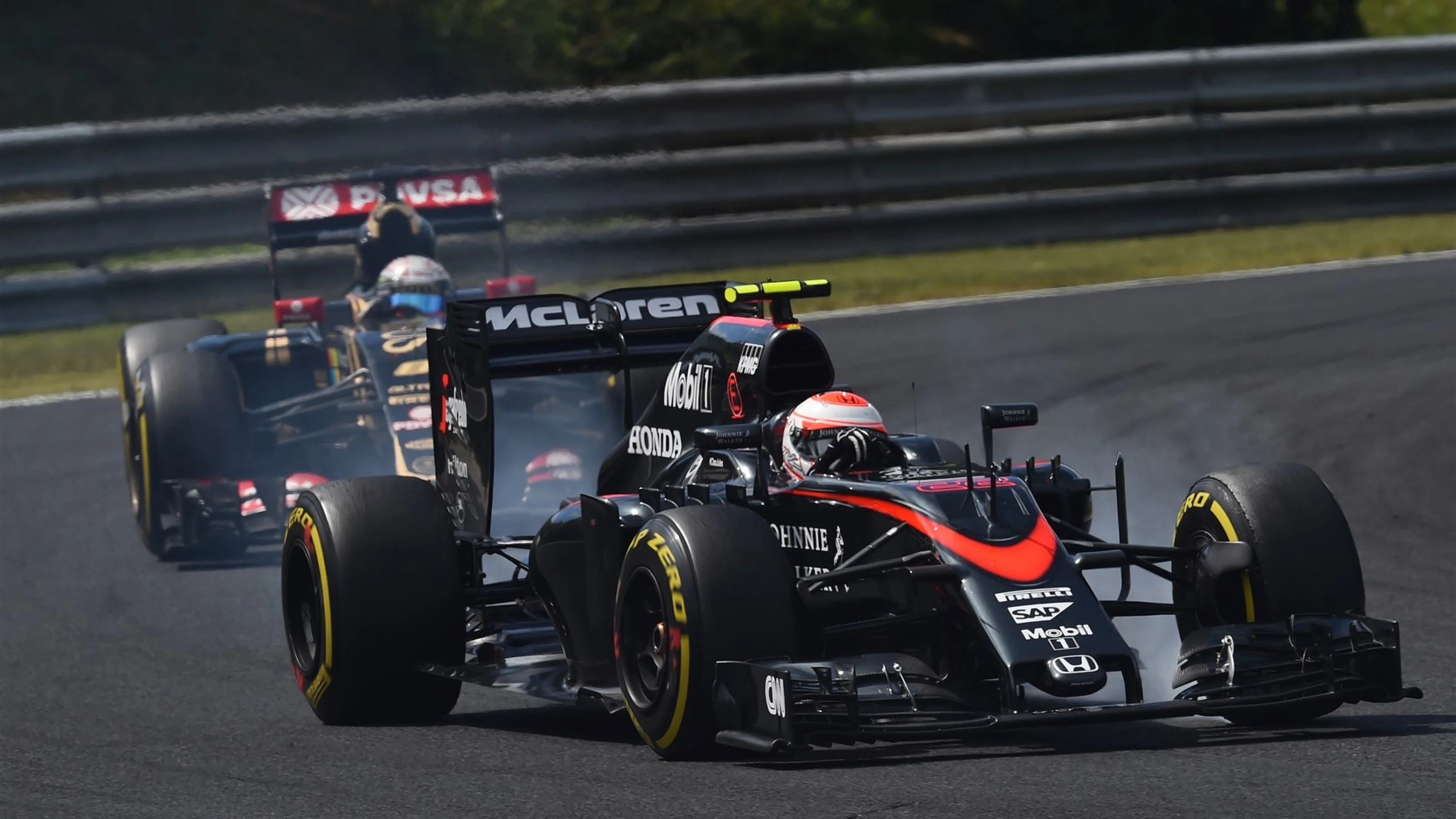 Jenson Button (GBR) McLaren MP4-30 leads Romain Grosjean (FRA) Lotus E23 Hybrid at Formula One