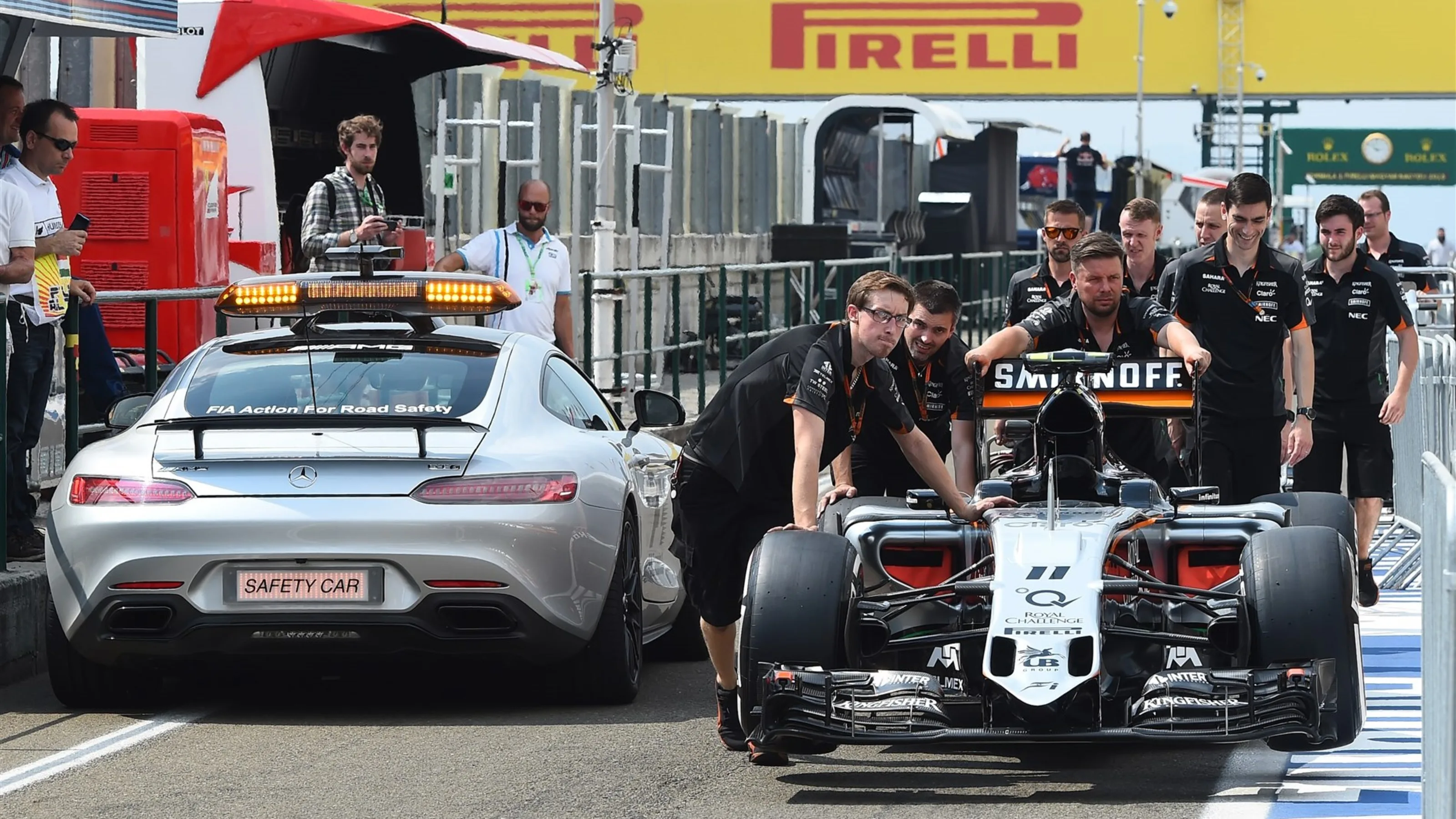 FIA safety car passes the Force India VJM08 as its pushed down the pitlane by mechanics at Formula
