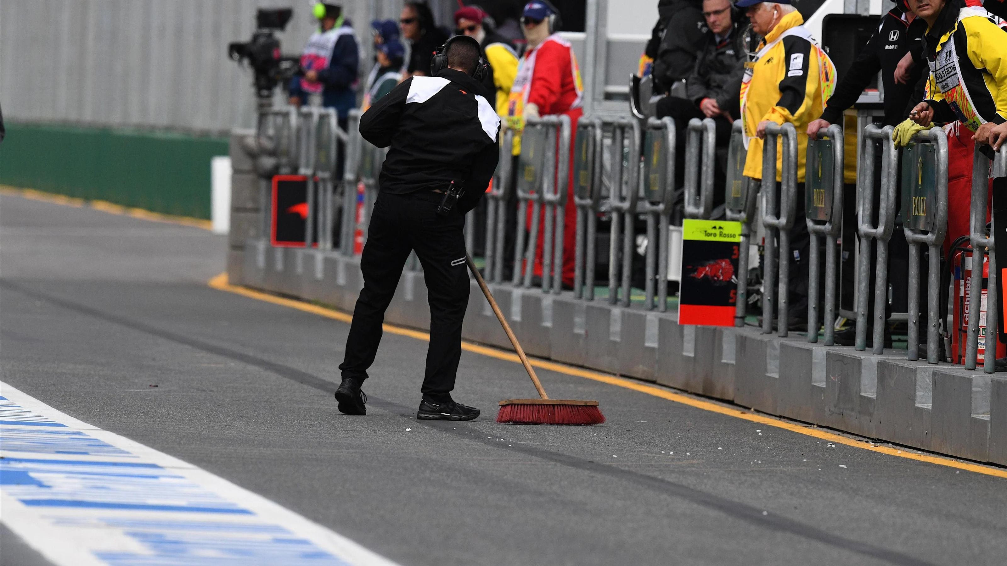 Mechanic sweeps pit lane at Formula One World Championship, Rd1, Australian Grand Prix, Qualifying,