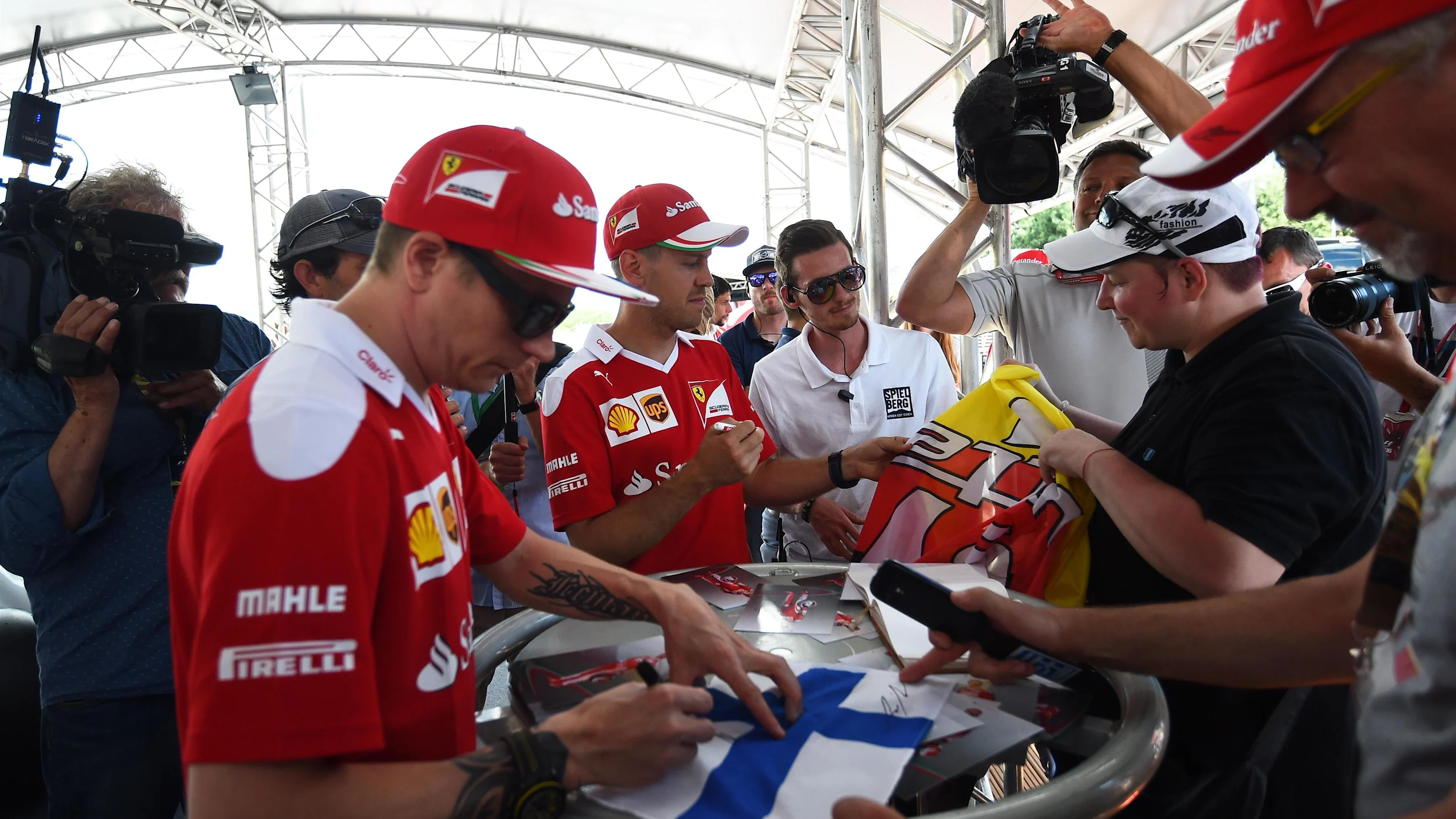 Kimi Raikkonen (FIN) Ferrari and Sebastian Vettel (GER) Ferrari sign autographs for the fans at