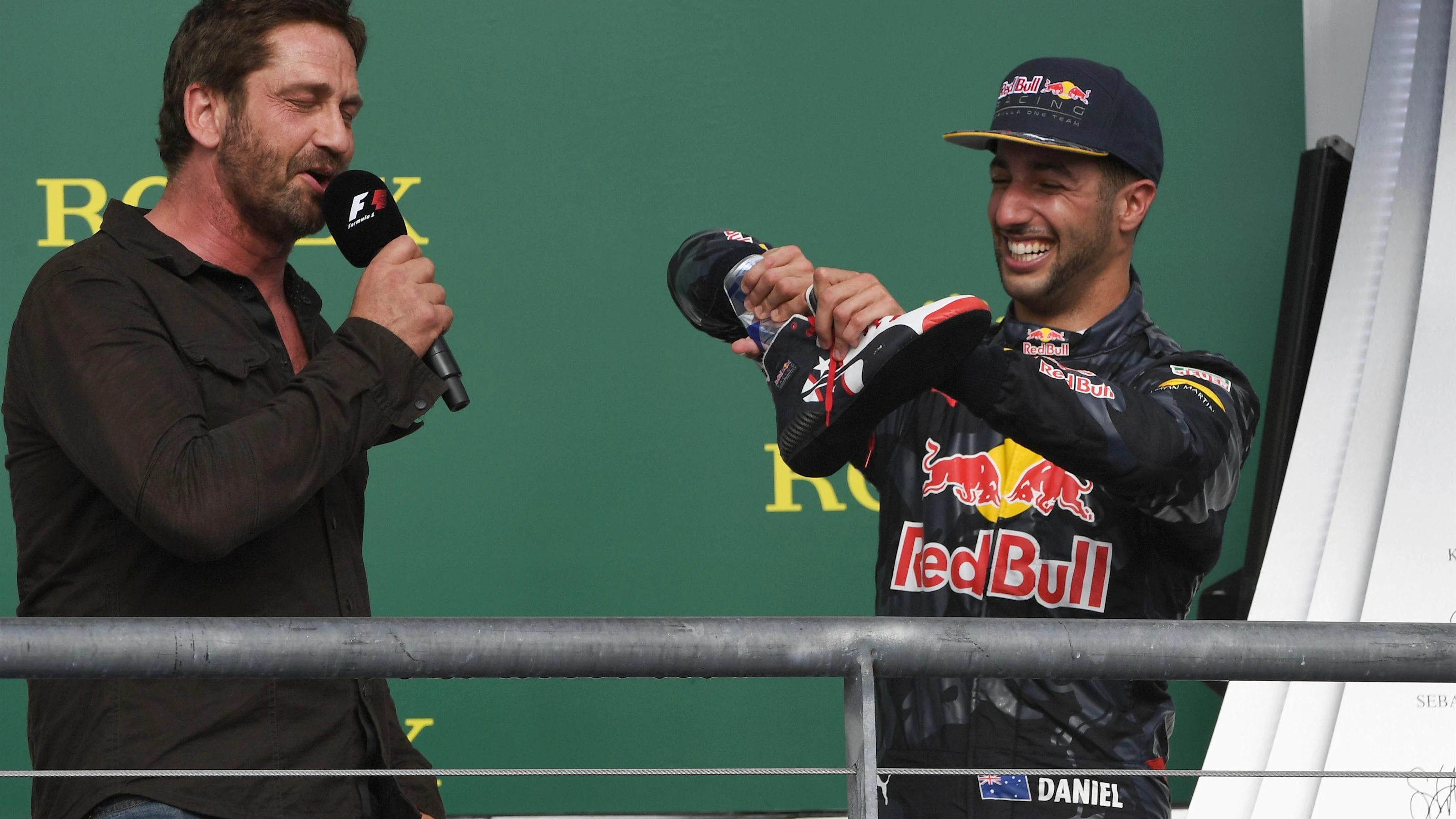 Daniel Ricciardo (AUS) Red Bull Racing offers Gerard Butler (GBR) Actor a drink from his shoe on