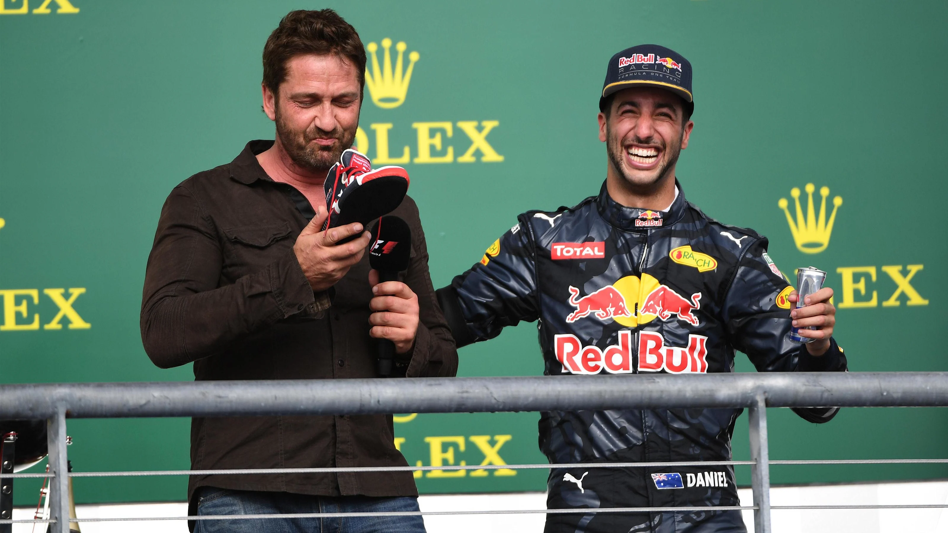 Daniel Ricciardo (AUS) Red Bull Racing offers Gerard Butler (GBR) Actor a drink from his shoe on