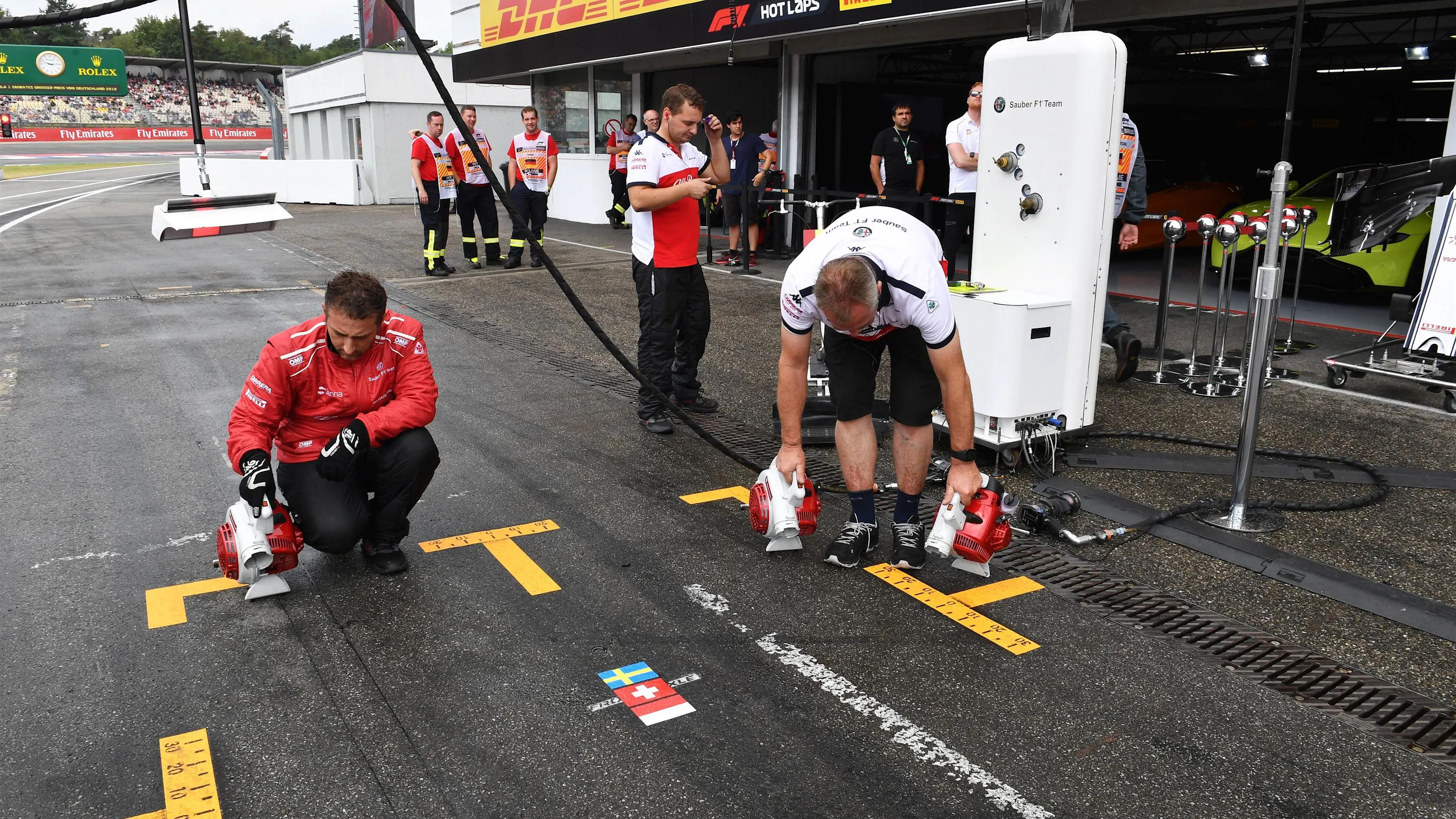 Alfa Romeo Sauber F1 Team mechanics dry the pit box at Formula One World Championship, Rd11, German
