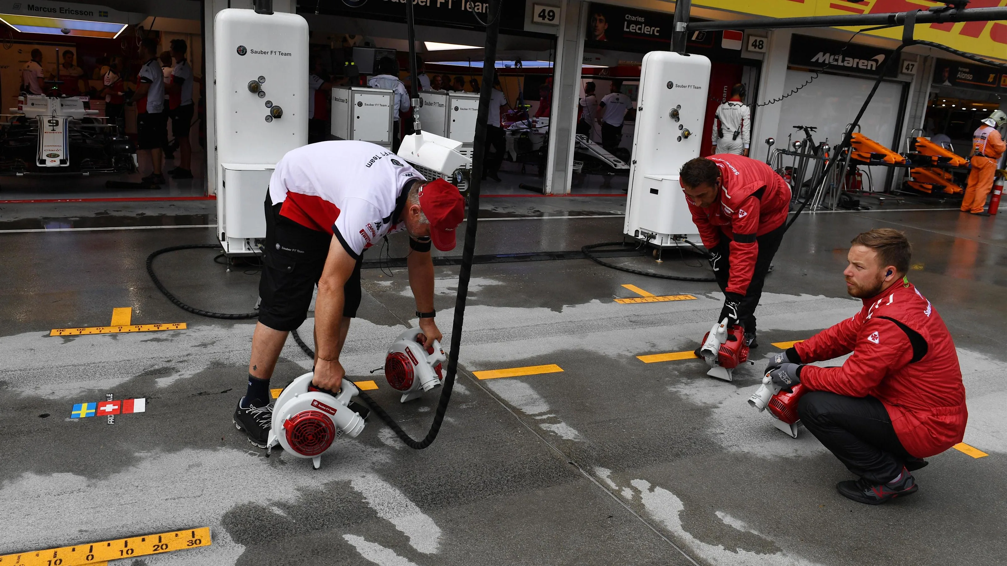 Alfa Romeo Sauber F1 Team mechanics dry the pit box at Formula One World Championship, Rd12,