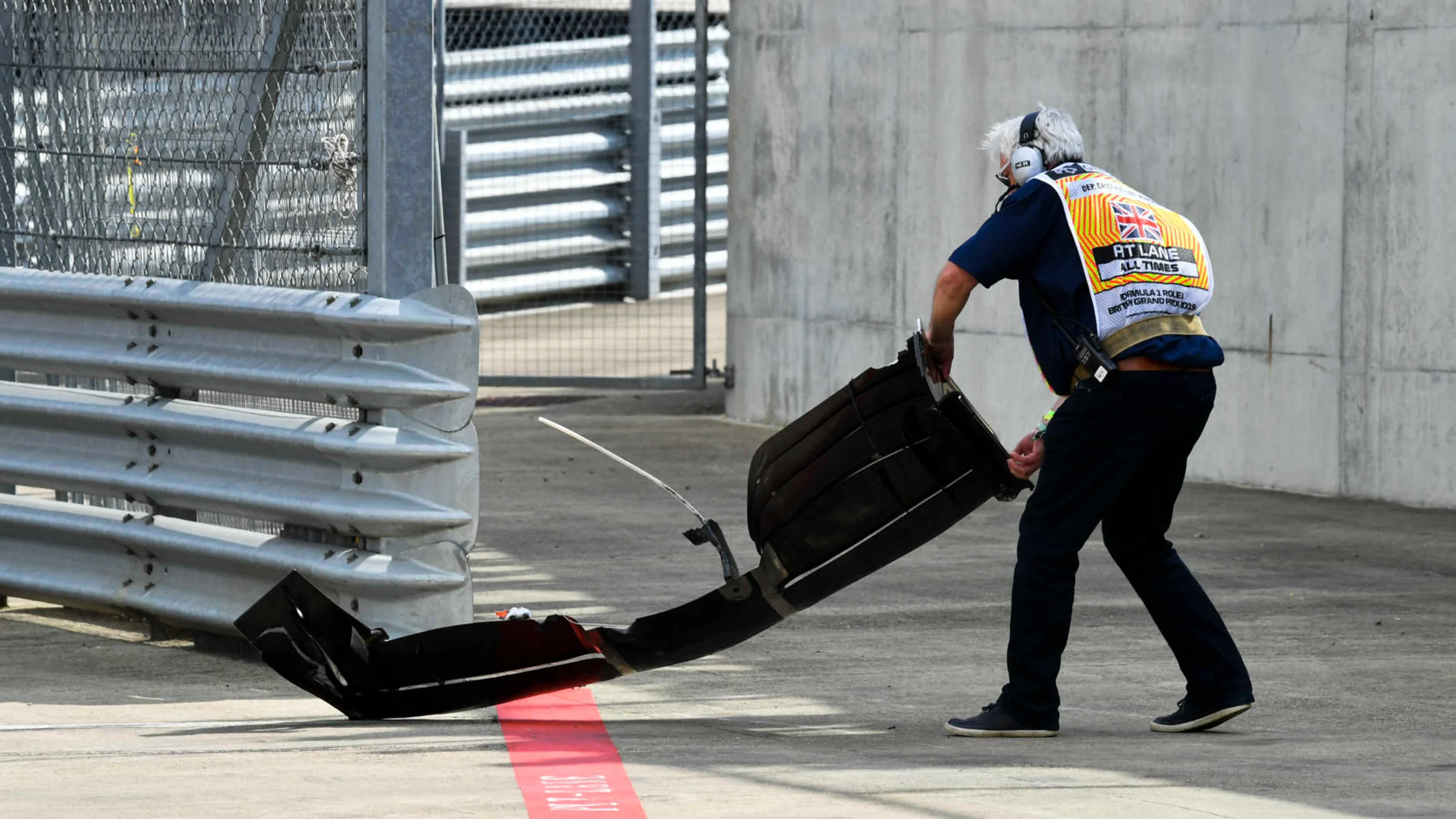 SILVERSTONE, UNITED KINGDOM - JULY 12: A Marshal removes the front wing of Romain Grosjean, Haas