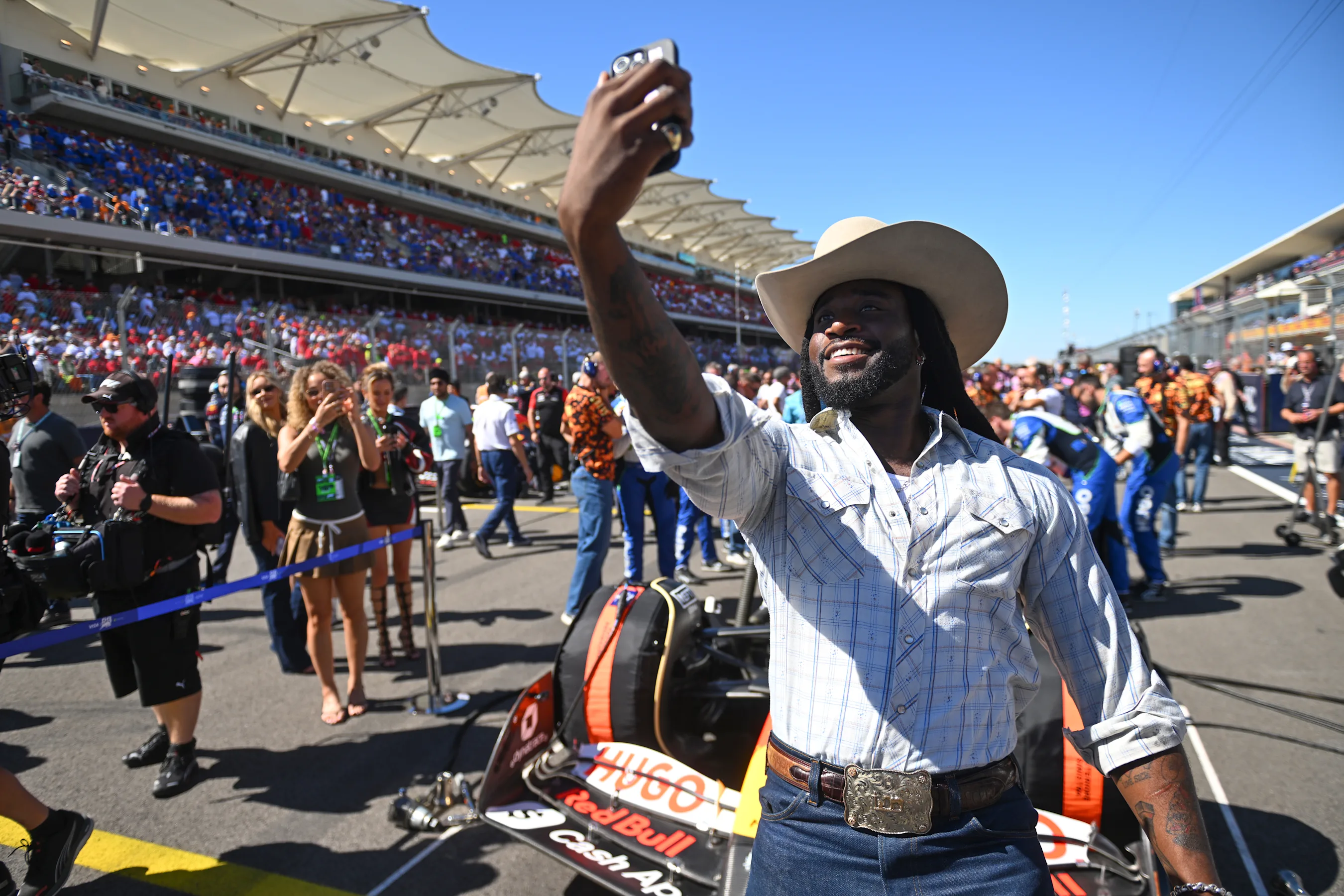 AUSTIN, TEXAS - OCTOBER 19: Shaboozey takes a selfie with the Visa Cash App Racing Bulls car on the
