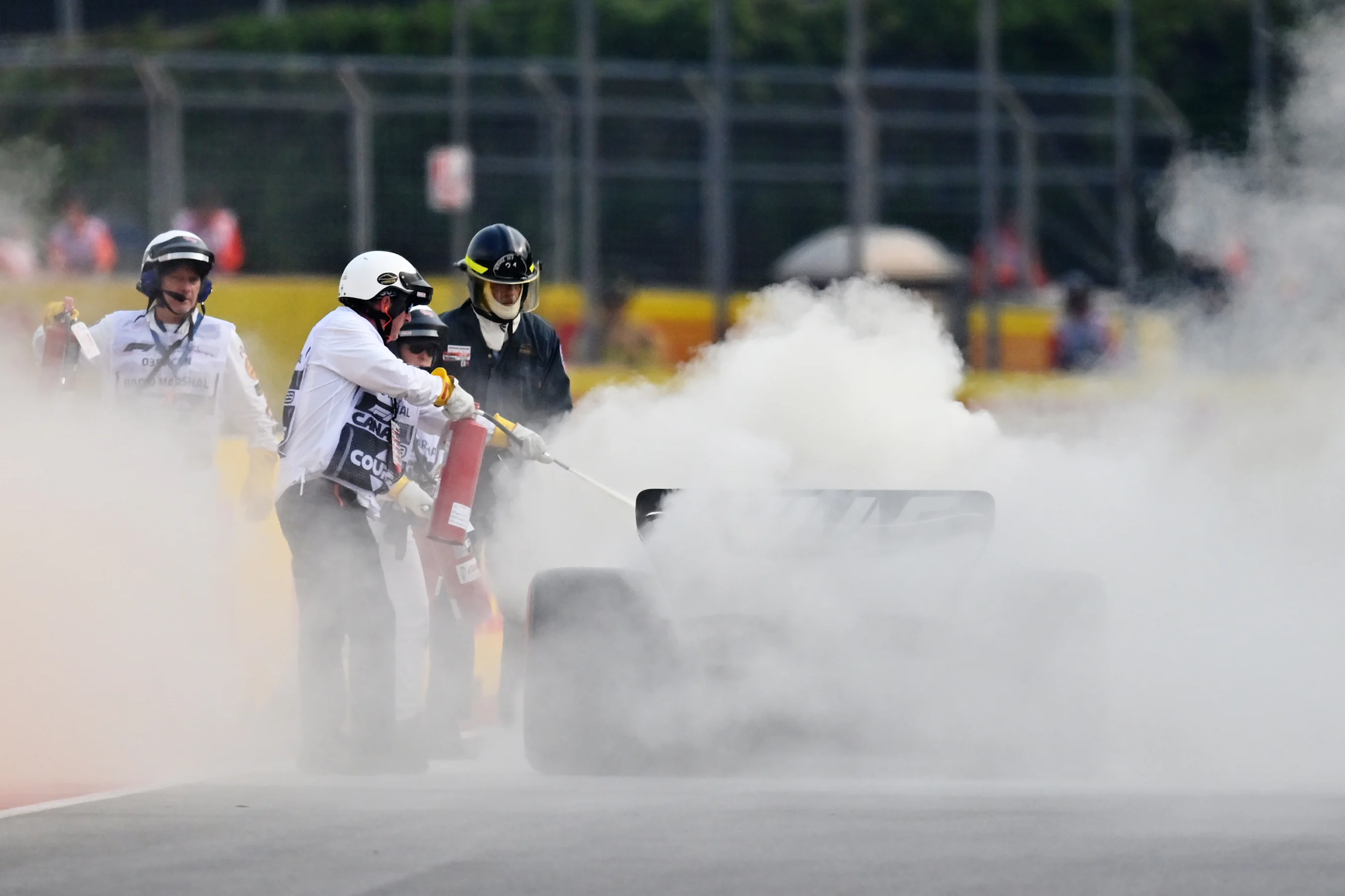 MONTREAL, QUEBEC - JUNE 16: Track marshals use fire extinguishers on the car of Nico Hulkenberg of