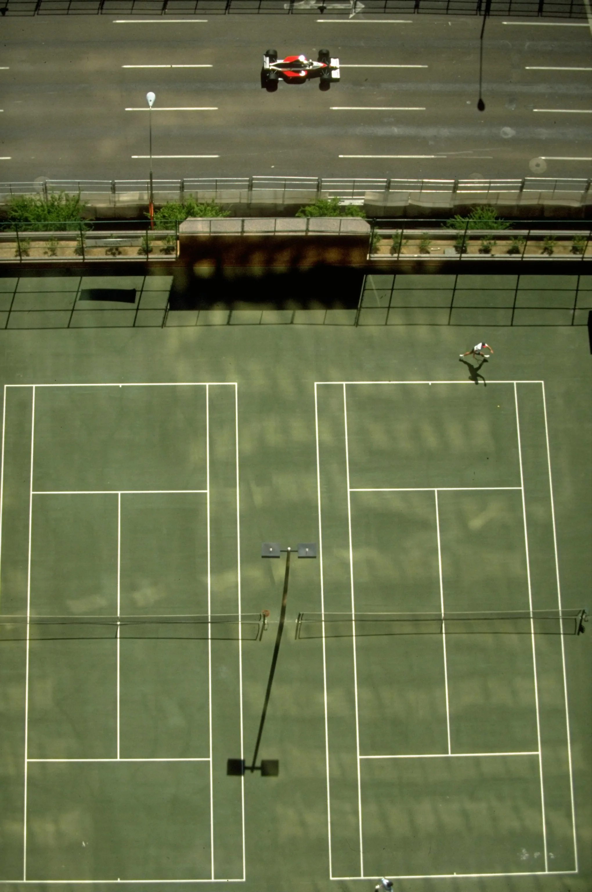 1991: Aerial view of a Formula One car driving past tennis courts during the US Grand Prix at the