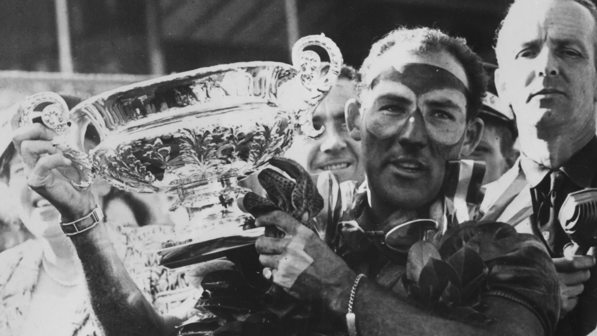 17th July 1955:  English motor-racing driver Stirling Moss, the winner's laurels around his neck,