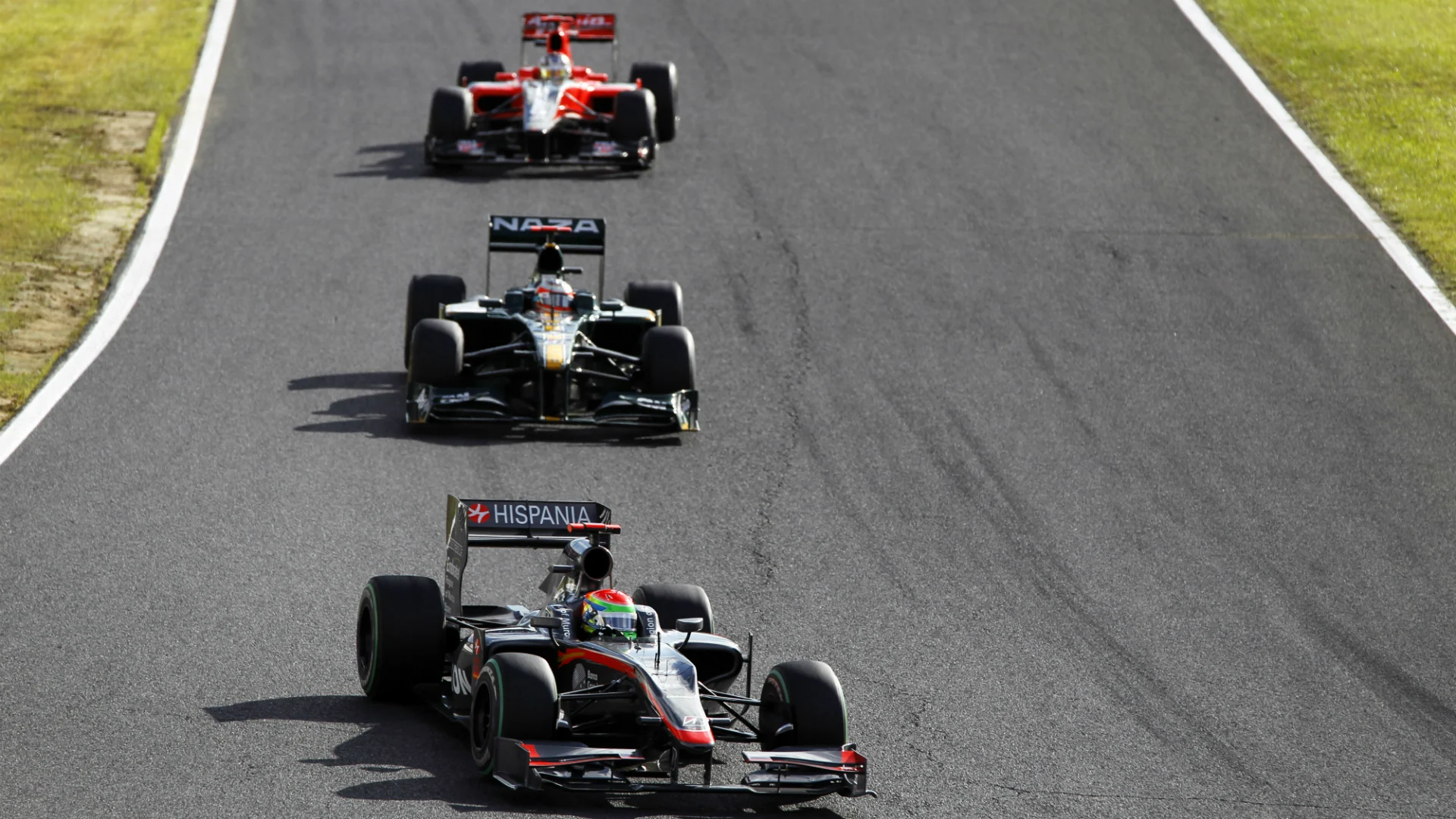 Sakon Yamamoto, HRT, 16th position, leads Jarno Trulli, Lotus, 13th position, and Timo Glock,