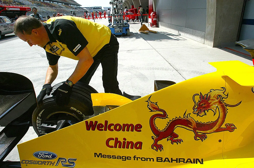 SHANGHAI, CHINA: A technical worker with the Jordan team dusts off a tyre as a traditional Chinese