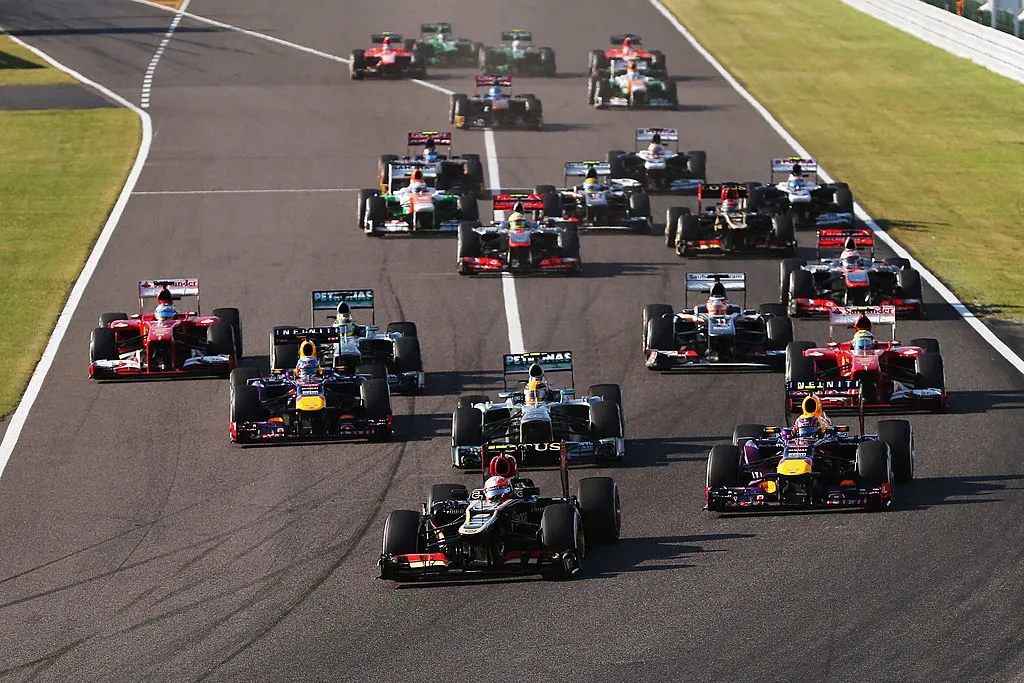 SUZUKA, JAPAN - OCTOBER 13: Romain Grosjean (C) of France and Lotus takes the lead at the start of