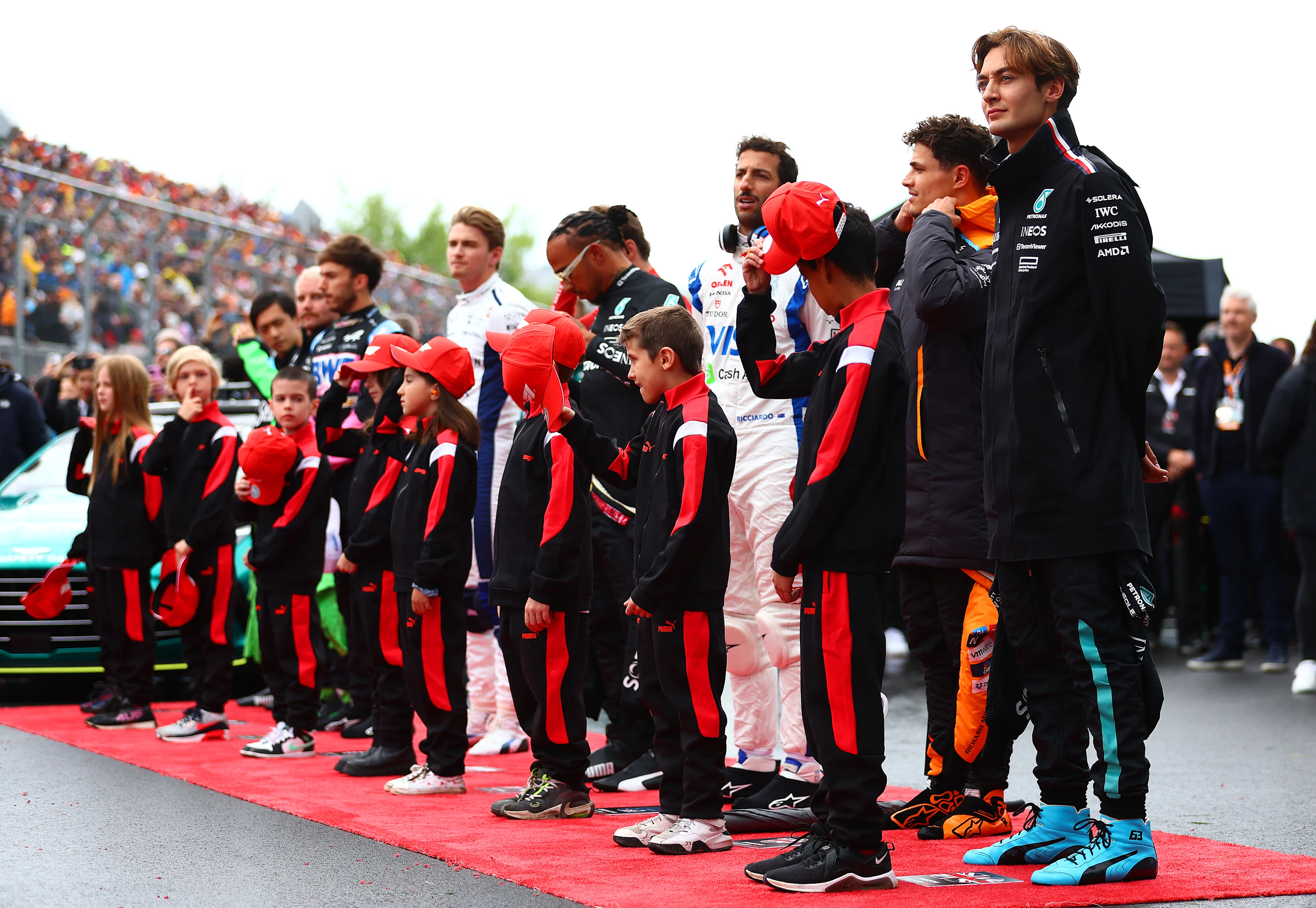 MONTREAL, QUEBEC - JUNE 09: Drivers stand with grid kids for the national anthem on the grid prior