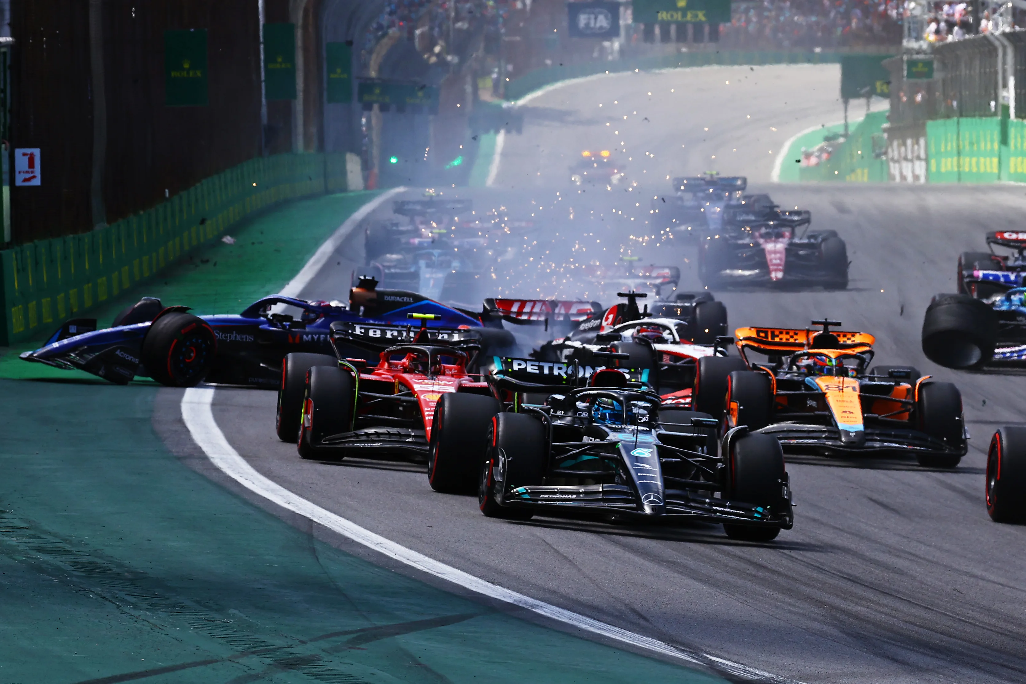 SAO PAULO, BRAZIL - NOVEMBER 05: Alexander Albon of Thailand driving the (23) Williams FW45 Mercedes and Kevin Magnussen of Denmark driving the (20) Haas F1 VF-23 Ferrari (obscured) crash into turn one at the start during the F1 Grand Prix of Brazil at Autodromo Jose Carlos Pace on November 05, 2023 in Sao Paulo, Brazil. (Photo by Mark Thompson/Getty Images)