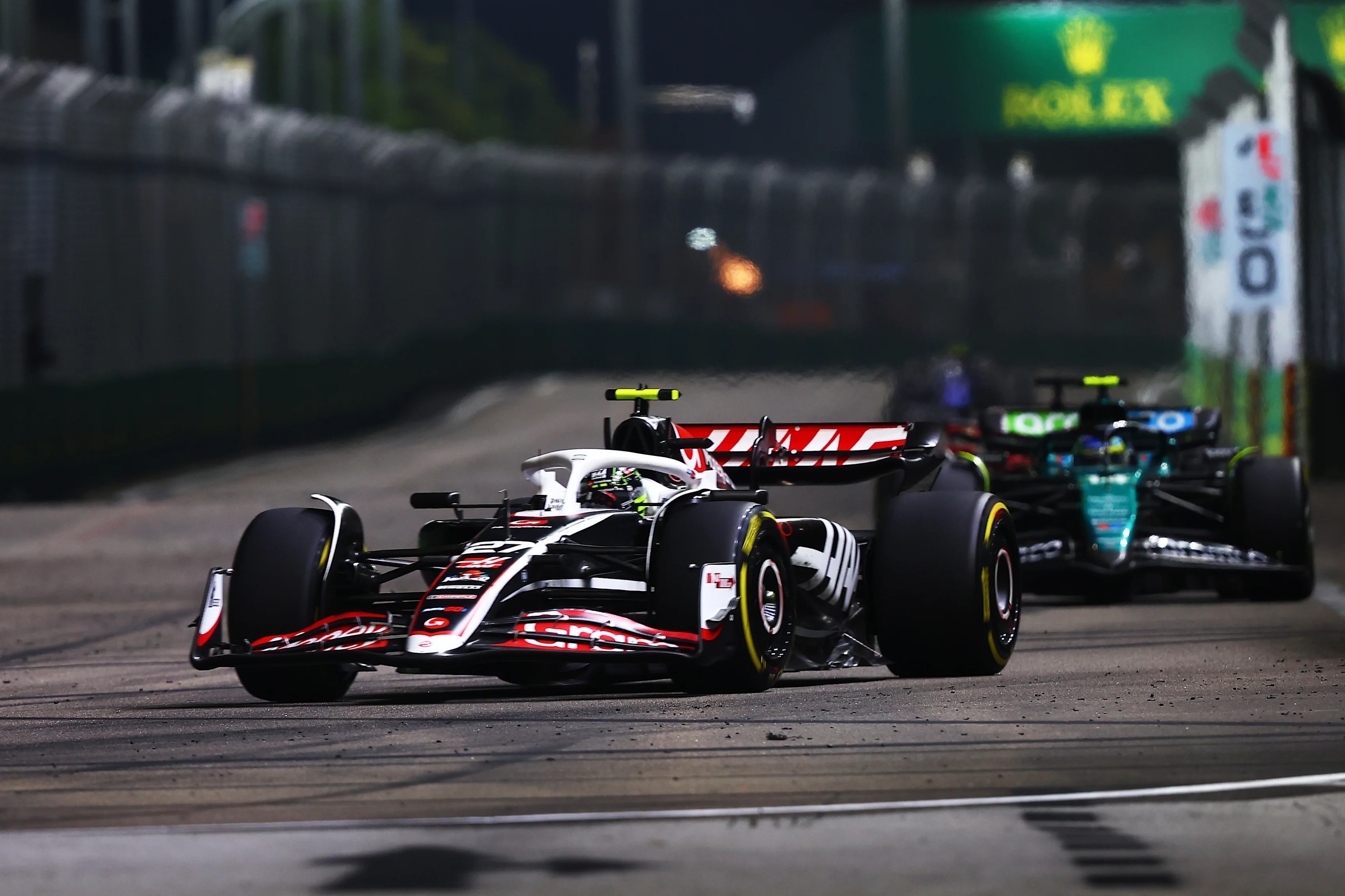 SINGAPORE, SINGAPORE - SEPTEMBER 22: Nico Hulkenberg of Germany driving the (27) Haas F1 VF-24 Ferrari leads Fernando Alonso driving the (14) Aston Martin AMR24 Mercedes on track during the F1 Grand Prix of Singapore. (Photo by Joe Portlock/Getty Images)