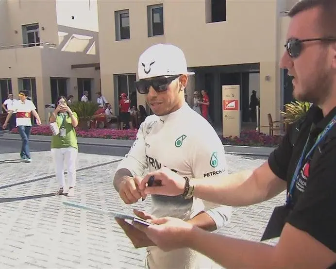 2014 title contender Lewis Hamilton signs an autograph on his way to the Mercedes garage ahead of FP3 © FOWC Ltd. No reproduction without permission.