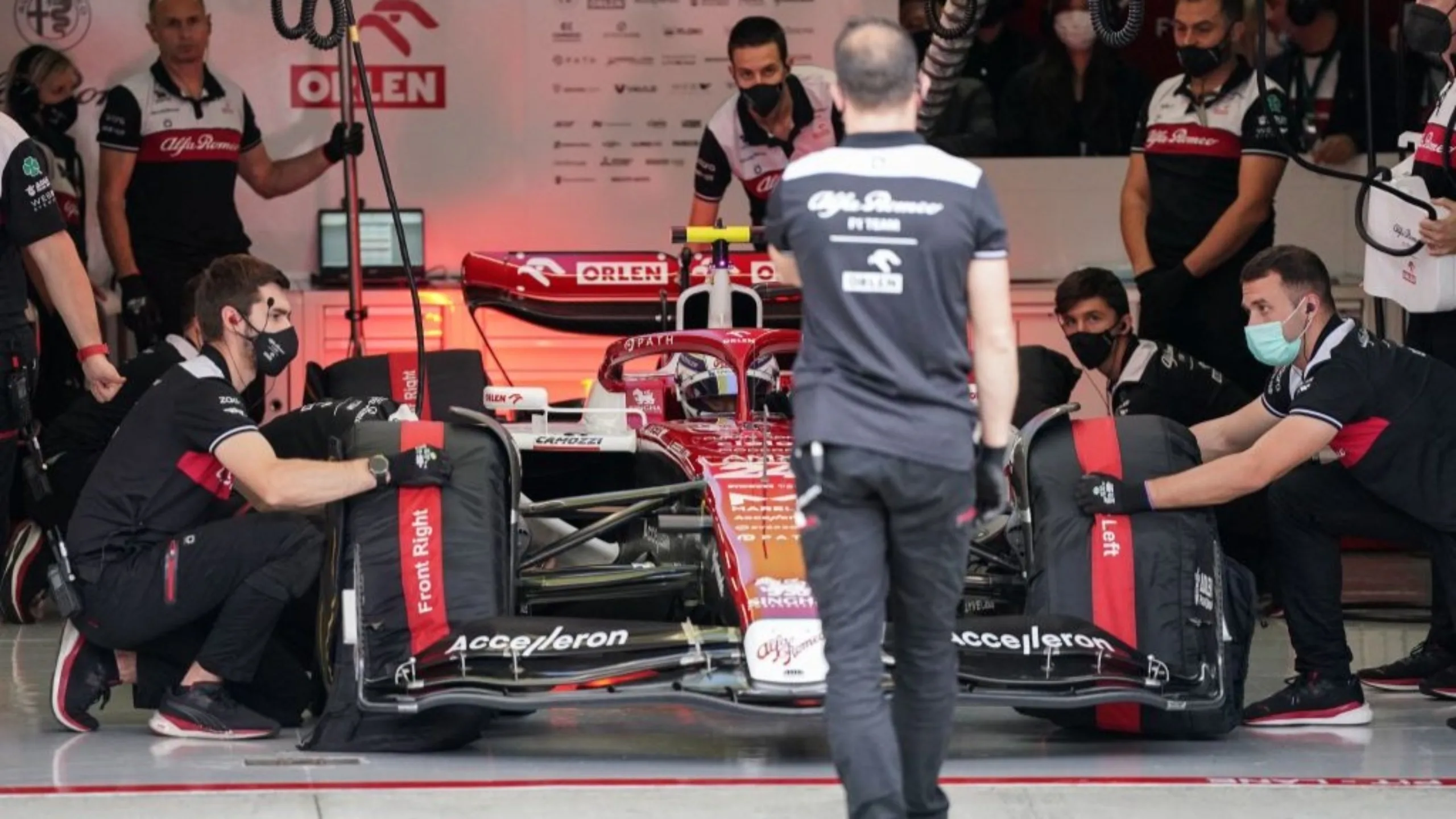 Mechanics work on the car of Alfa Romeo's Chinese driver Zhou Guanyu in the pit during the