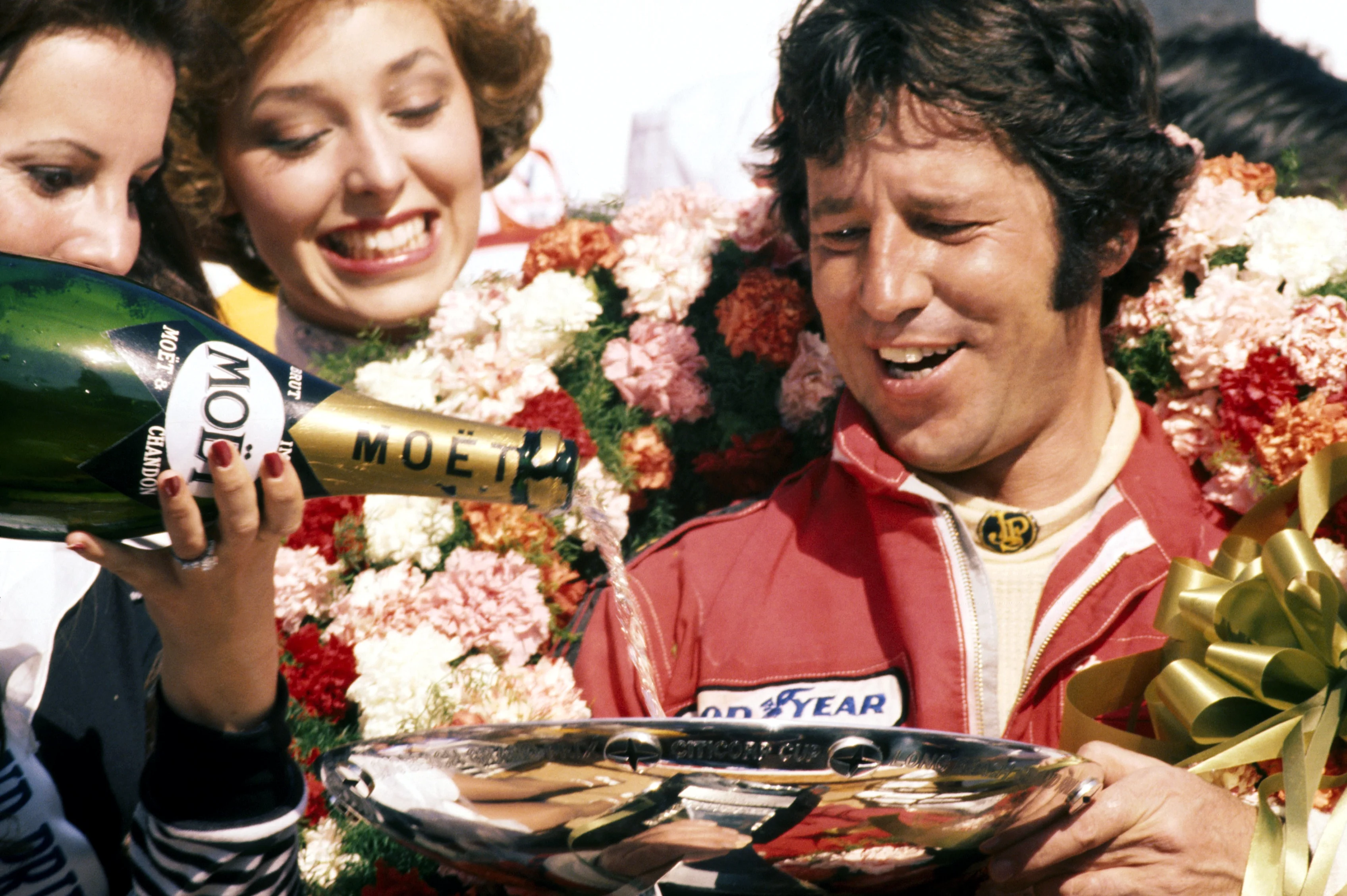 Mario Andretti (USA) Lotus celebrates a popular home GP victory on the podium by having his trophy