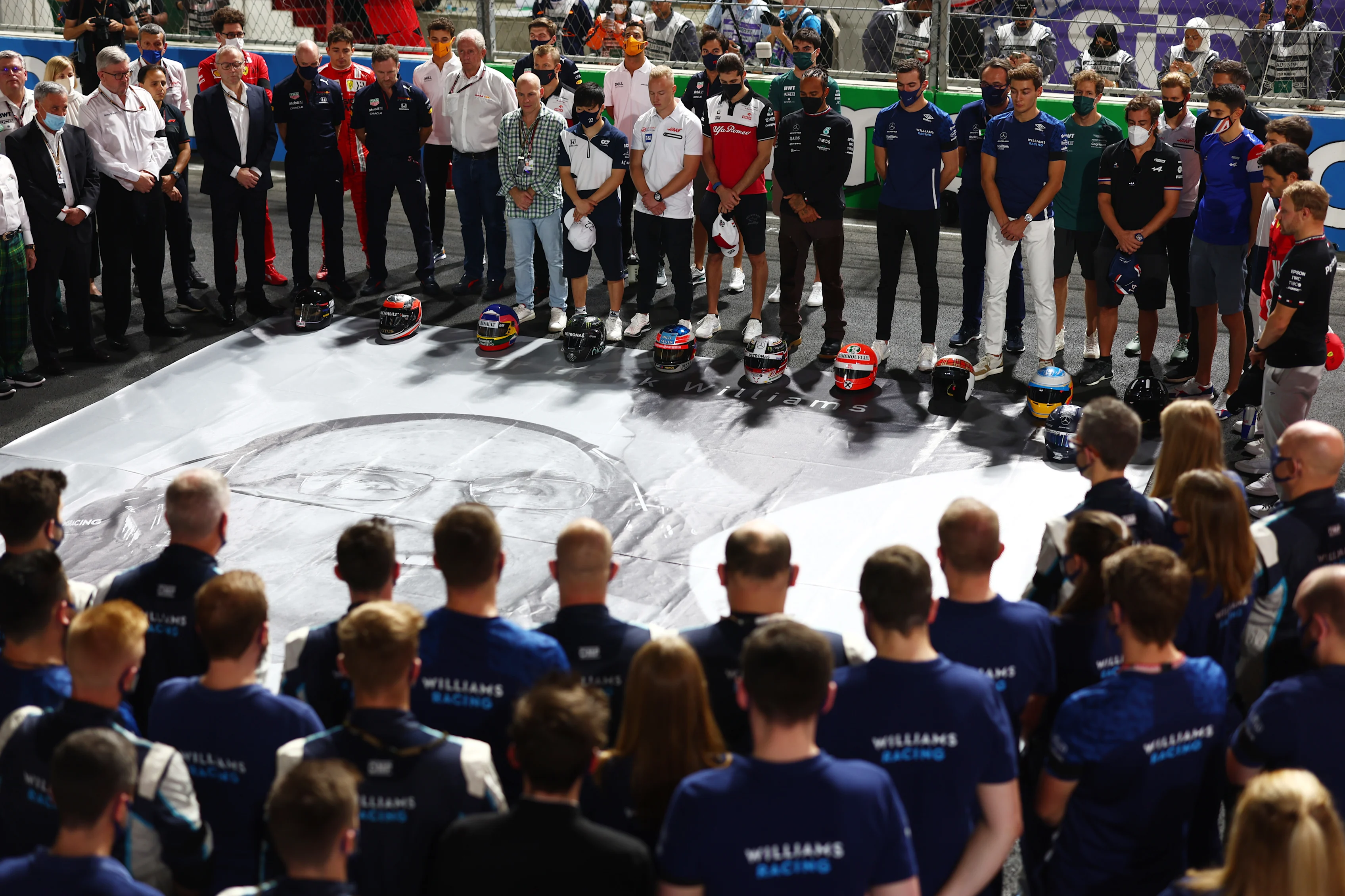JEDDAH, SAUDI ARABIA - DECEMBER 05: The F1 community stands for a minutes silence in tribute to the late Sir Frank Williams ahead of the F1 Grand Prix of Saudi Arabia at Jeddah Corniche Circuit on December 05, 2021 in Jeddah, Saudi Arabia. (Photo by Mark Thompson/Getty Images)