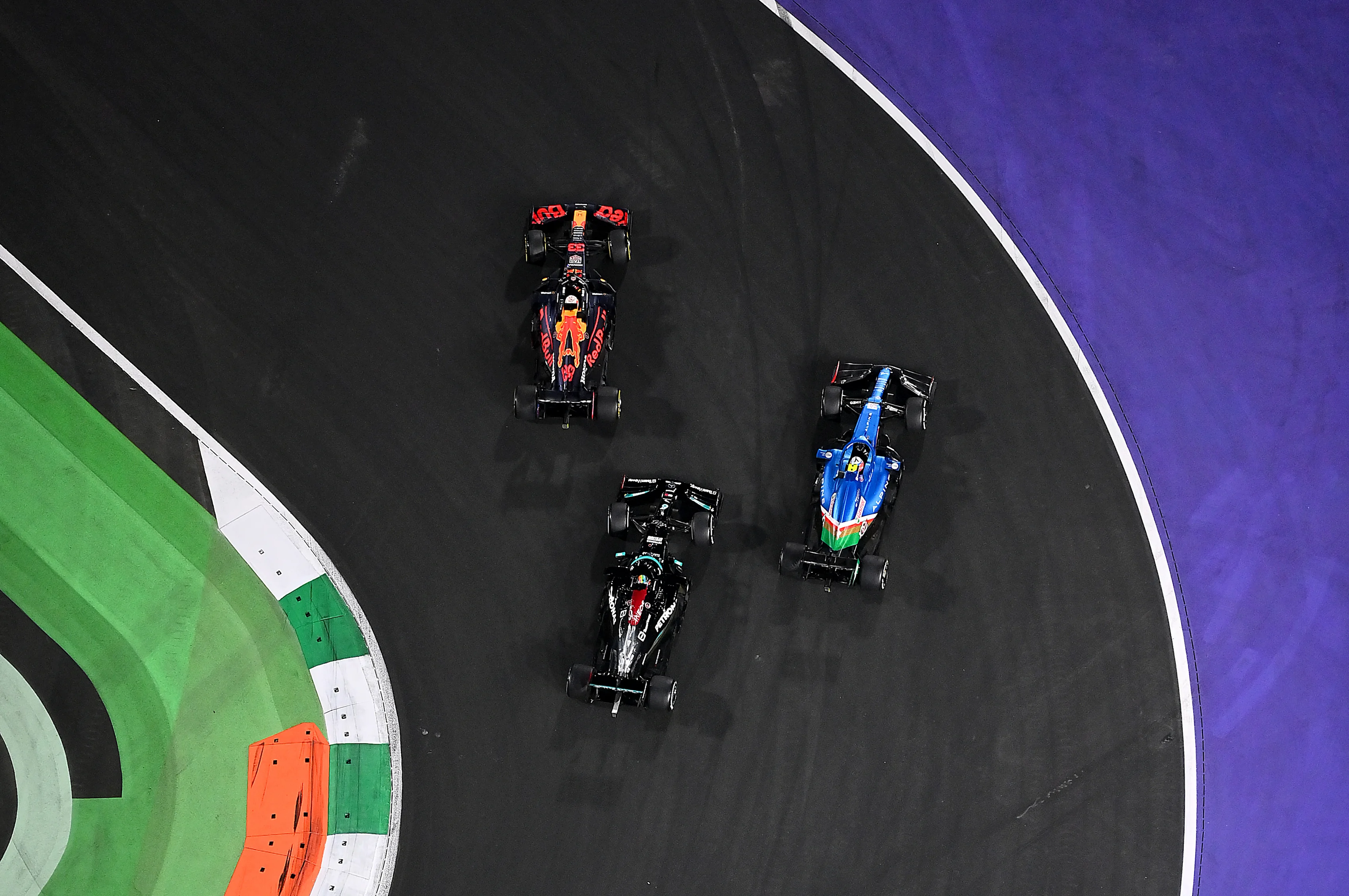 JEDDAH, SAUDI ARABIA - DECEMBER 05: Max Verstappen of the Netherlands driving the (33) Red Bull Racing RB16B Honda leads the field into turn one ahead of Lewis Hamilton of Great Britain driving the (44) Mercedes AMG Petronas F1 Team Mercedes W12 and Esteban Ocon of France driving the (31) Alpine A521 Renault at the second restart during the F1 Grand Prix of Saudi Arabia at Jeddah Corniche Circuit on December 05, 2021 in Jeddah, Saudi Arabia. (Photo by Dan Mullan/Getty Images)