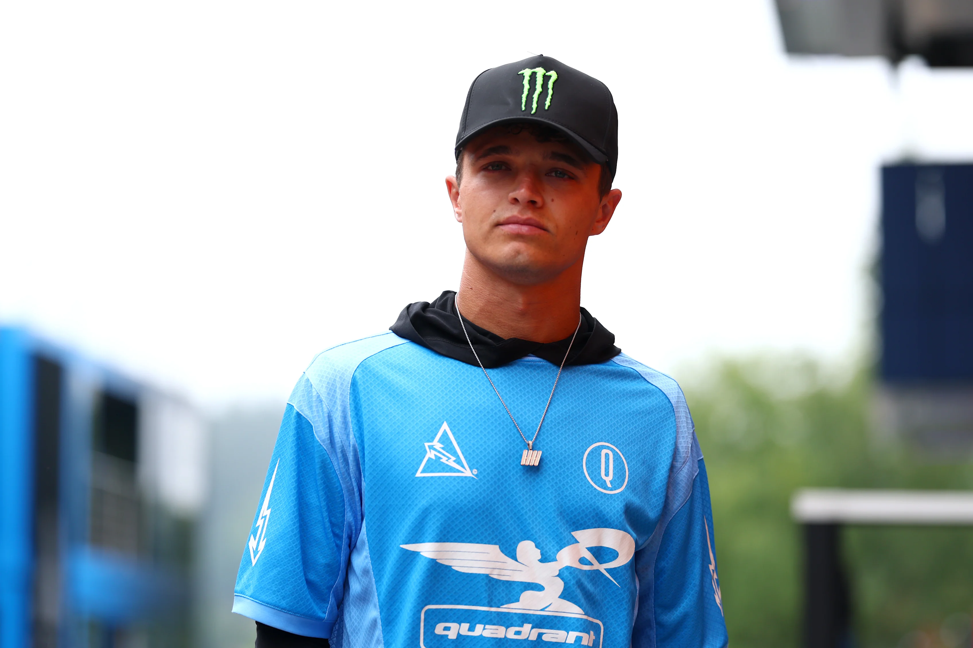 Lando walks the paddock ahead of the 2025 Belgian Grand Prix wearing a jersey style shirt from his own brand Quadrant. Swipe to see more