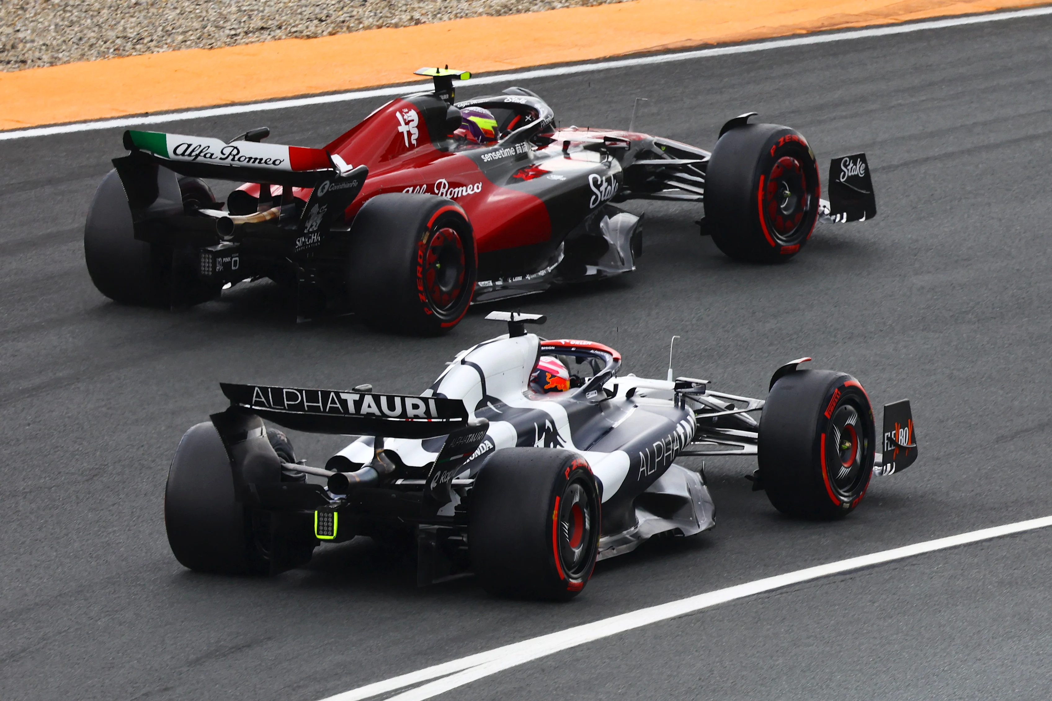ZANDVOORT, NETHERLANDS - AUGUST 27: Liam Lawson of New Zealand driving the (40) Scuderia AlphaTauri AT04 and Zhou Guanyu of China driving the (24) Alfa Romeo F1 C43 Ferrari battle for track position during the F1 Grand Prix of The Netherlands at Circuit Zandvoort on August 27, 2023 in Zandvoort, Netherlands. (Photo by Mark Thompson/Getty Images)