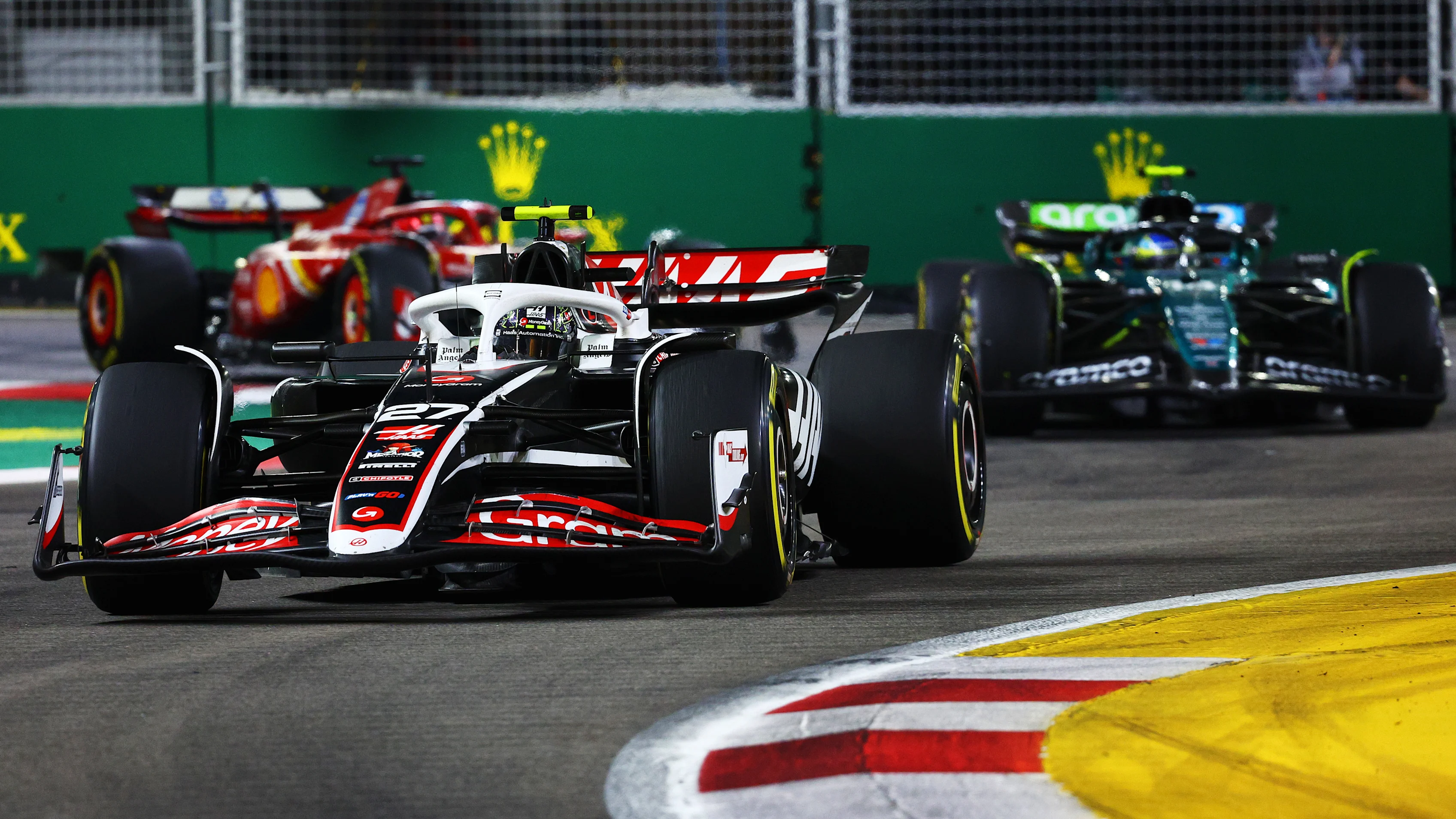 SINGAPORE, SINGAPORE - SEPTEMBER 22: Nico Hulkenberg of Germany driving the (27) Haas F1 VF-24 Ferrari leads Fernando Alonso of Spain driving the (14) Aston Martin AMR24 Mercedes on track during the F1 Grand Prix of Singapore at Marina Bay Street Circuit on September 22, 2024 in Singapore, Singapore. (Photo by Clive Rose - Formula 1/Formula 1 via Getty Images)
