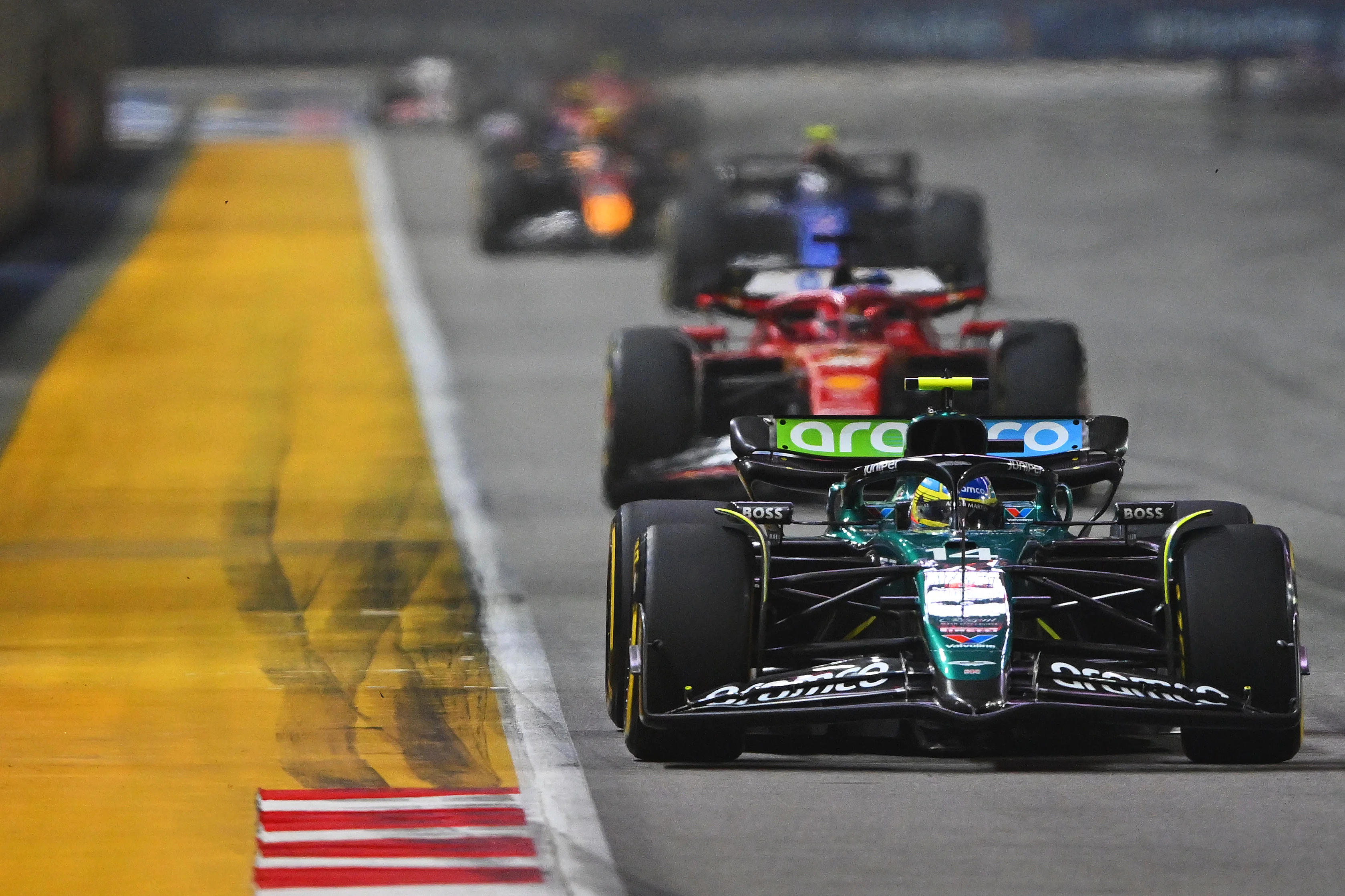 SINGAPORE, SINGAPORE - SEPTEMBER 22: Fernando Alonso of Spain driving the (14) Aston Martin AMR24 Mercedes leads Charles Leclerc of Monaco driving the (16) Ferrari SF-24 on track during the Grand Prix of Singapore. (Photo by Rudy Carezzevoli/Getty Images)