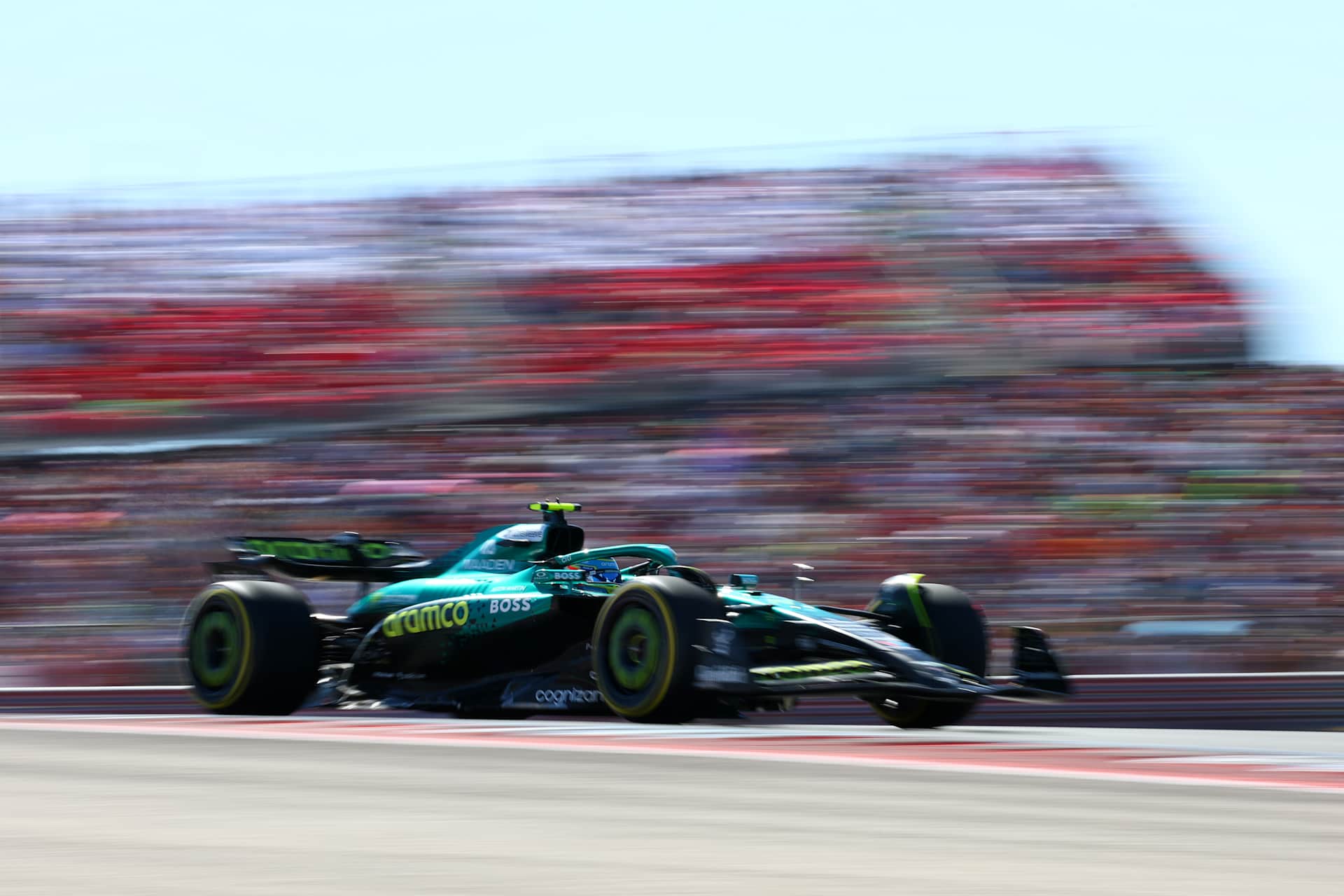Fernando Alonso’s green Aston Martin passing grandstands at COTA in 2025.