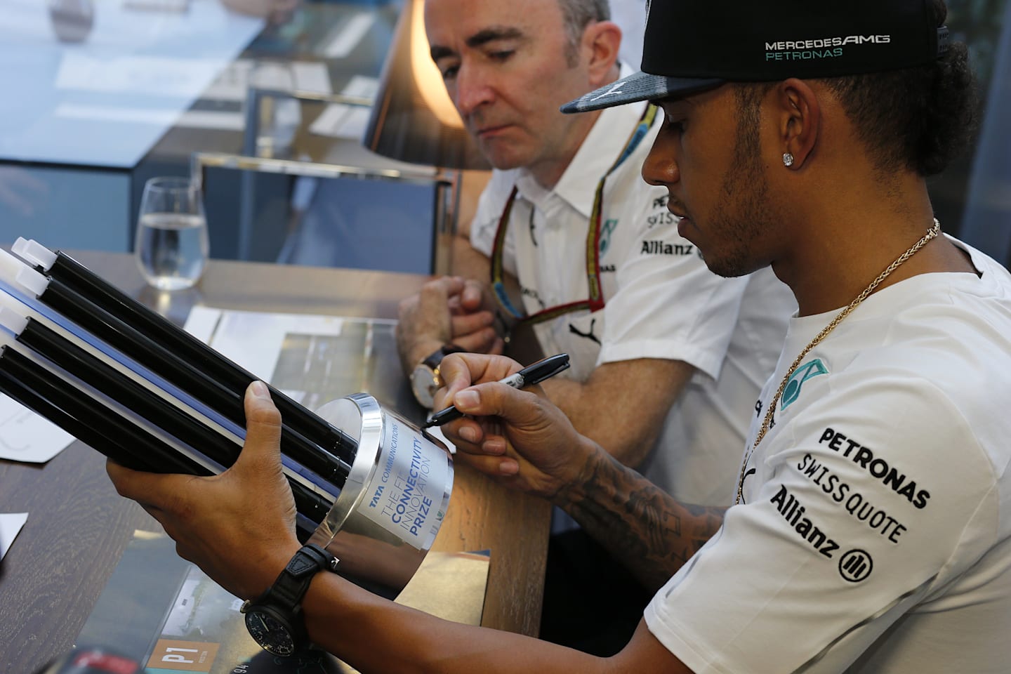 Mercedes' Lewis Hamilton, one of the judges in Tata Communications' inaugural F1 Connectivity Innovation Prize, adds his signature to the winners' trophy. © Tata Communications