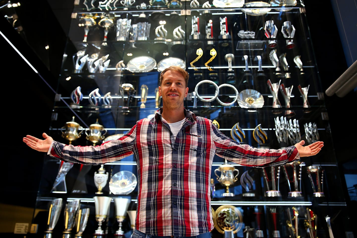 Outgoing Red Bull driver Sebastian Vettel poses with some of the trophies he won, Red Bull factory, Milton Keynes, December 2 2014. © Red Bull