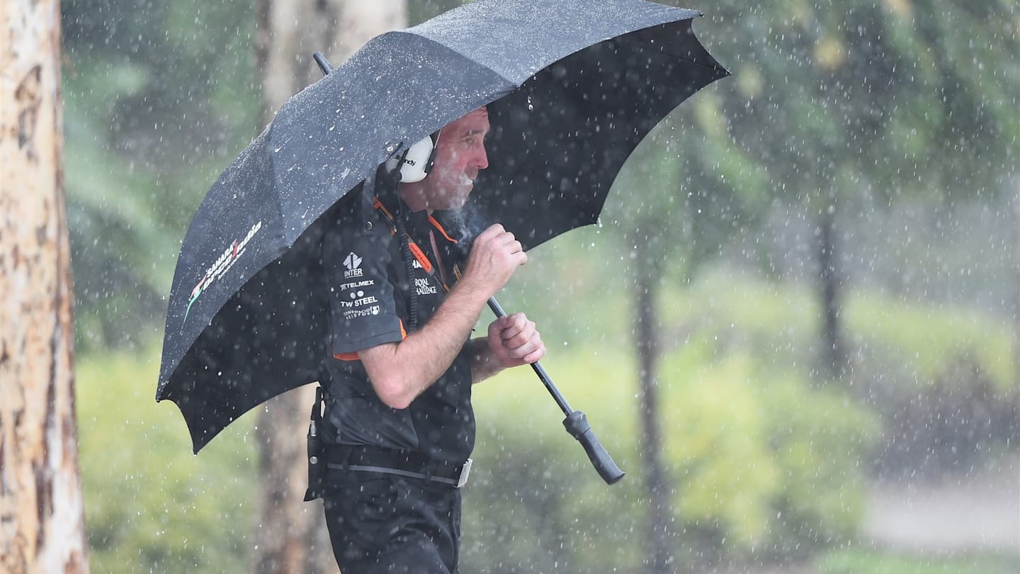 Force India mechanic with Action umbrella in the rain smoking a cigarette at Formula One World