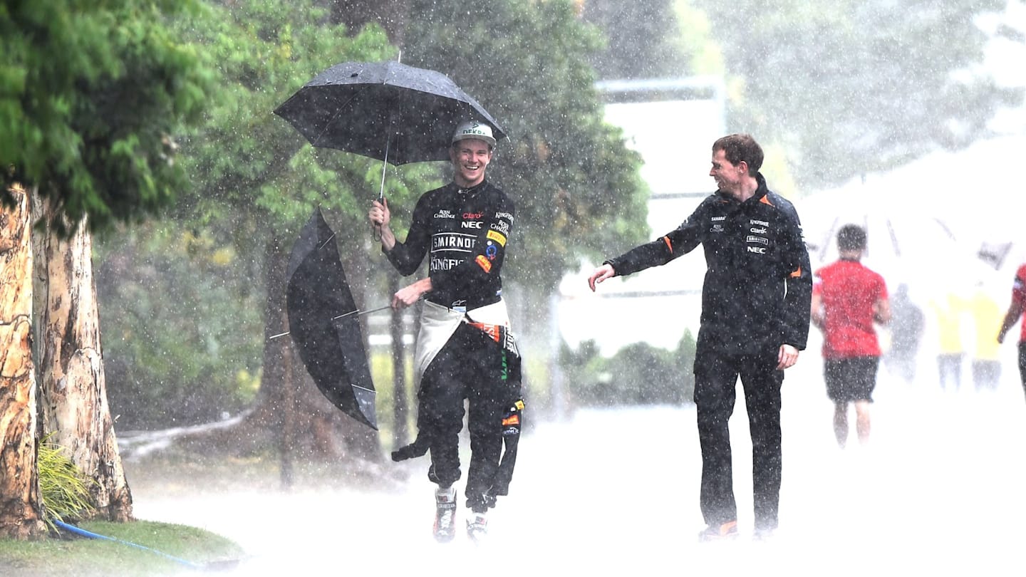 Nico Hulkenberg (GER) Force India F1 grabs Press Officer Will Hings (GBR) umbrella in the pouring