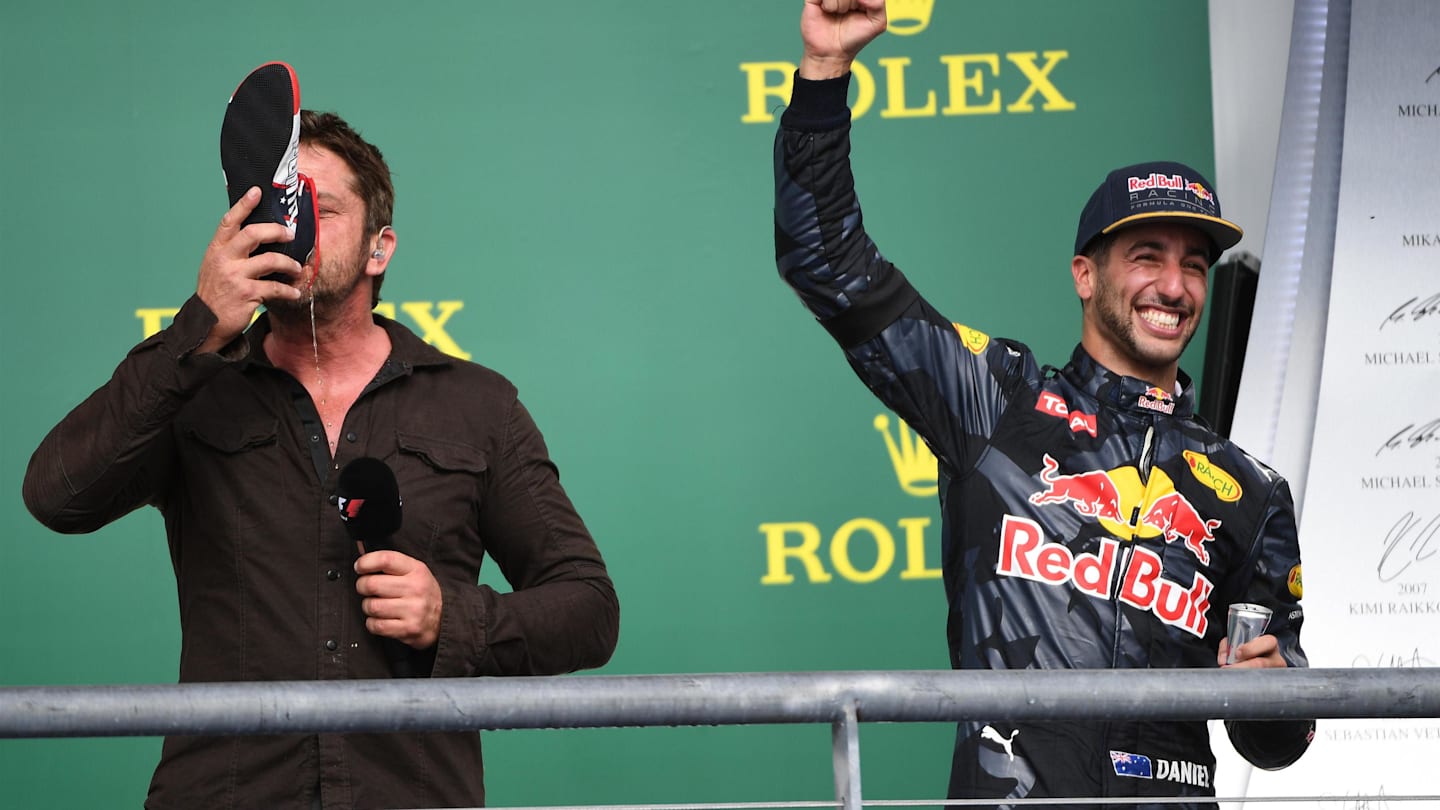 Gerard Butler (GBR) Actor drinks from the boot of Daniel Ricciardo (AUS) Red Bull Racing on the