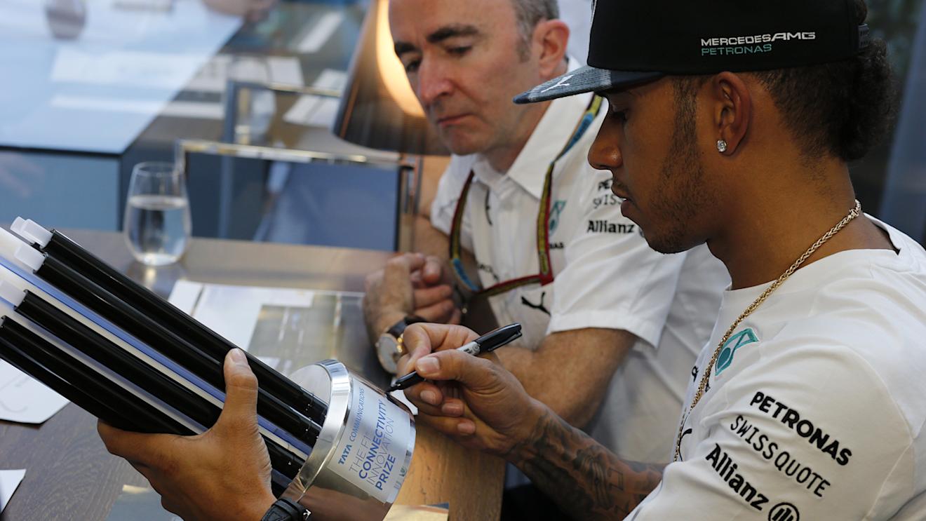 Mercedes' Lewis Hamilton, one of the judges in Tata Communications' inaugural F1 Connectivity Innovation Prize, adds his signature to the winners' trophy. © Tata Communications