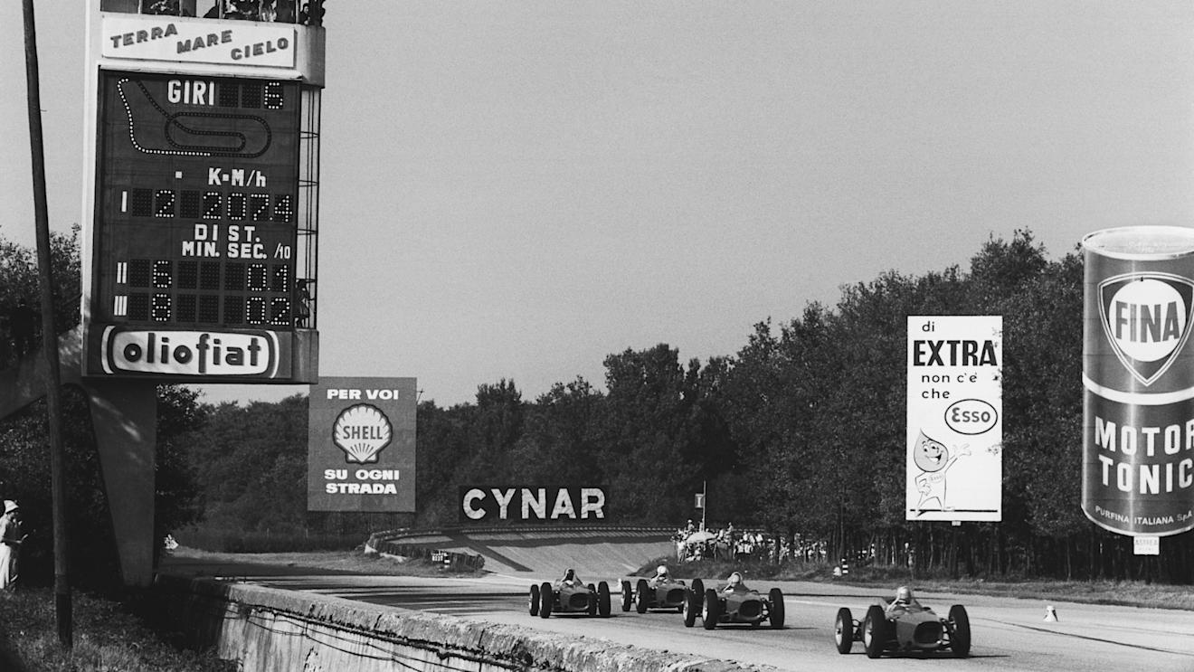 Four Ferrari Dino 156s race down the outside lane of the main straight in the 1961 race. Note the banking in the background, as well as the cones which divided the straight in two. World Copyright: LAT Photographic